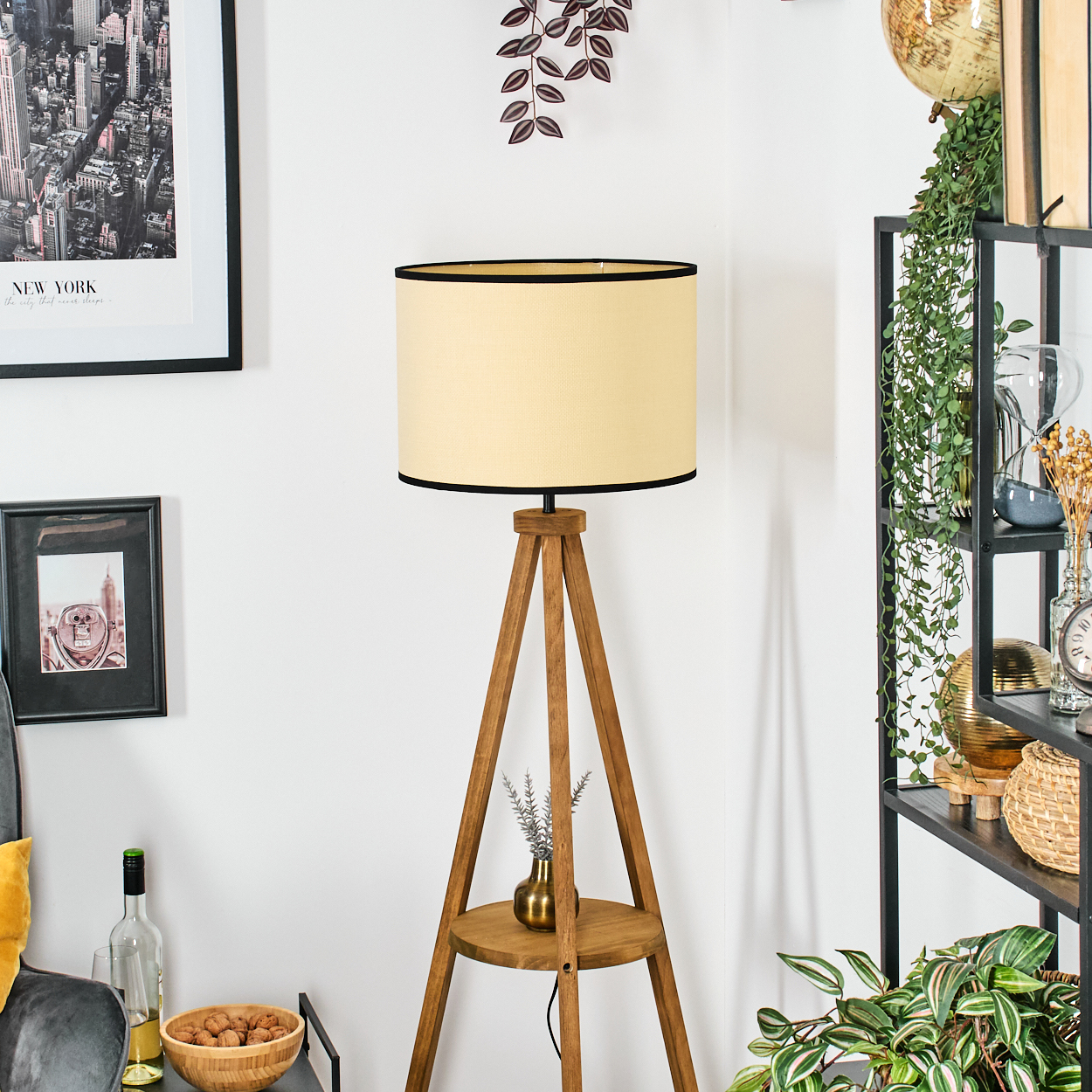 Eine Stehlampe aus Holz mit beigem Lampenschirm. Ein New York-Stadt-Druck und andere Dekorationsgegenstände sind im Hintergrund.