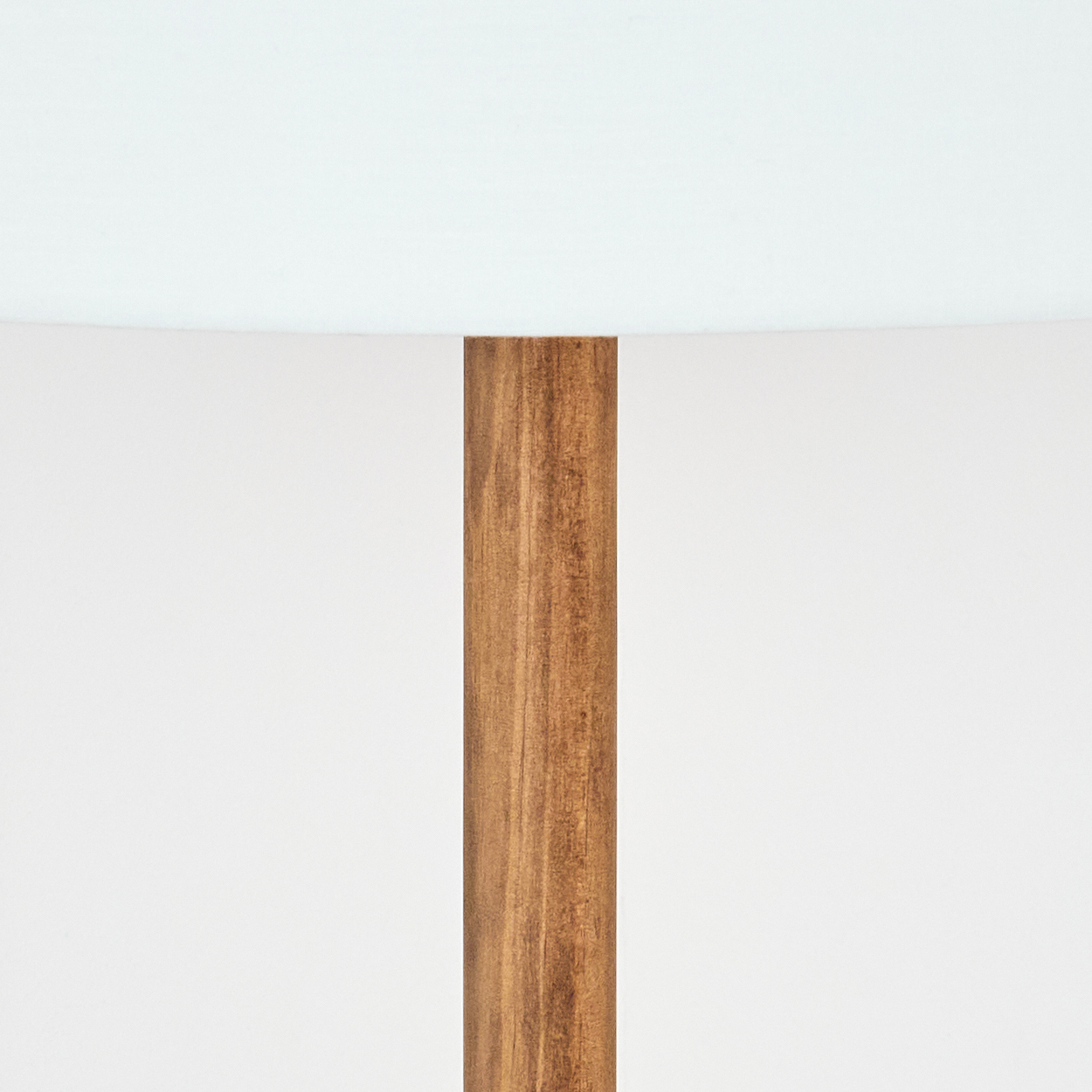 Ein hölzerner Lampenpfosten vor weißem Hintergrund, gekrönt von einem weißen Lampenschirm. Die Holzmaserung ist sichtbar.