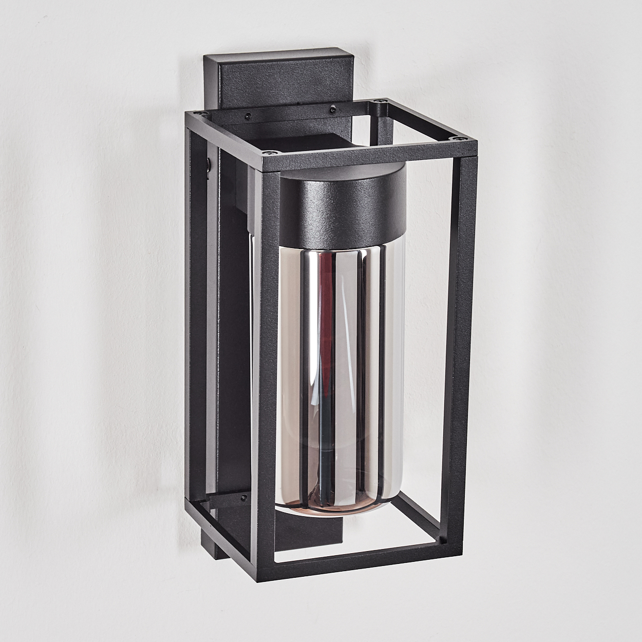 Schwarze Metall-Wandleuchte mit zylindrischem Glasschirm. An einer weißen Wand montiert. Die Lampe hat ein modernes, minimalistisches Design.