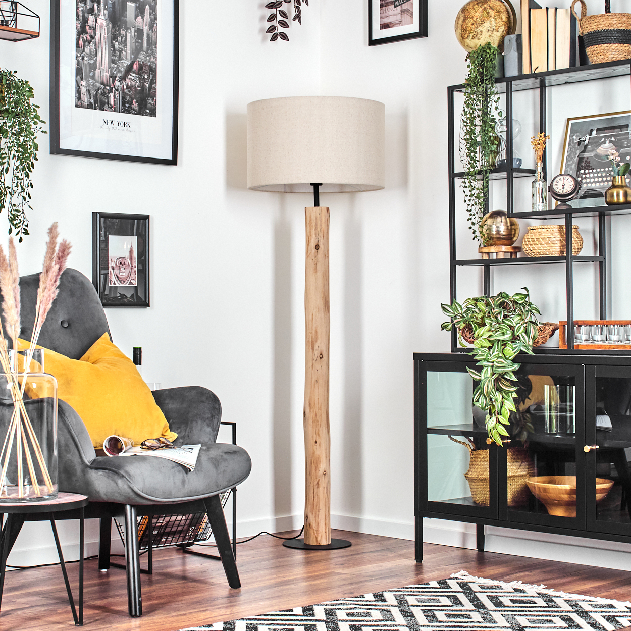 Ein gemütliches Wohnzimmer mit Stehlampe, Sessel und Schrank. Ein schwarz-weißer Teppich und Holzboden sind vorhanden.