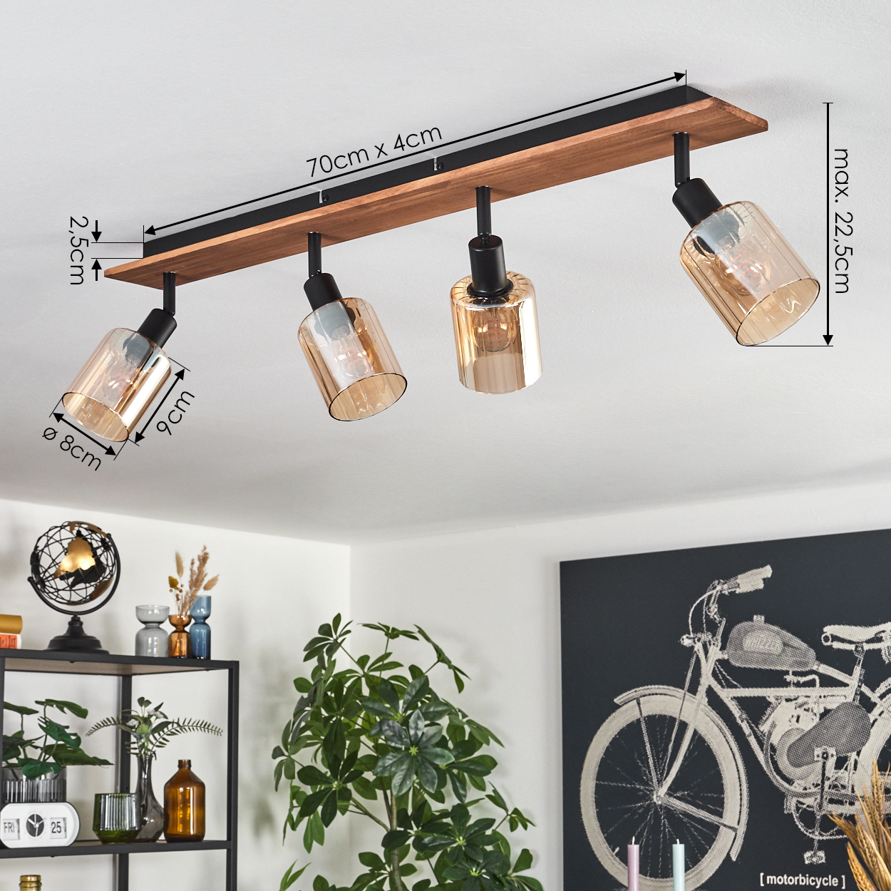 Deckenleuchte mit vier verstellbaren Strahlern, braune Holzplanke, schwarze Metallakzente. Enthält ein Fahrradkunstwerk und Pflanzen.