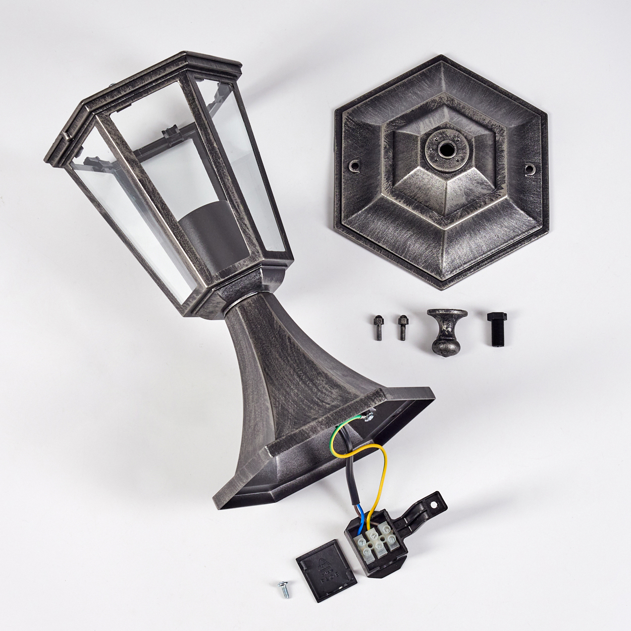 Zerlegte Außenlampe auf Weiß. Teile umfassen Lampenkopf, Sockel, Montageplatte, Schrauben und elektrische Komponenten.