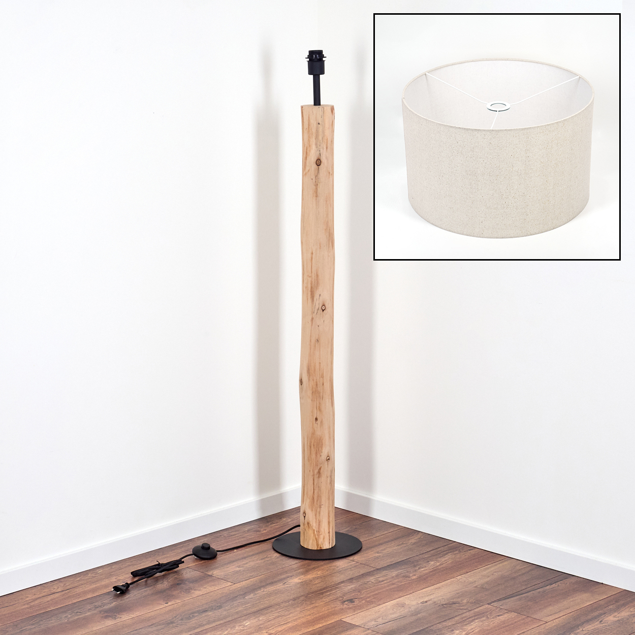 Eine Stehlampe aus Holz steht in einer Ecke. Sie hat einen hellbraunen, zylindrischen Lampenschirm. Der Sockel ist schwarz und rund.