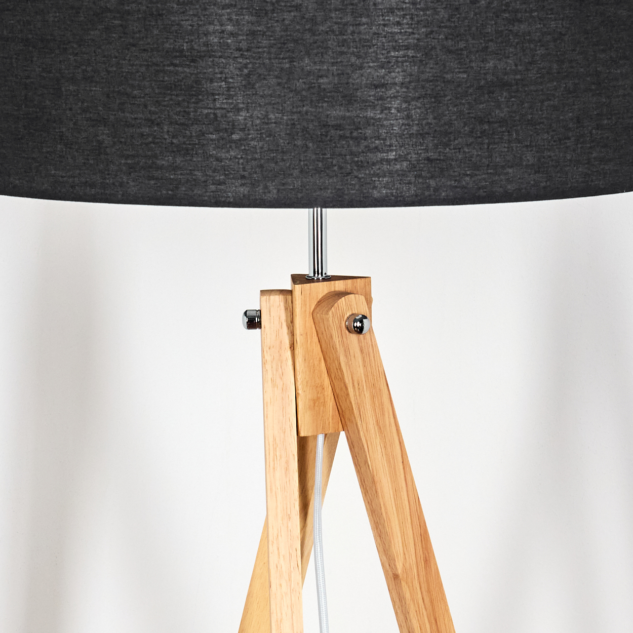 Eine Stehlampe mit Holzstativ und dunkelgrauem Lampenschirm. Die Holzbeine sind hellbraun, und ein weißes Kabel ist sichtbar.