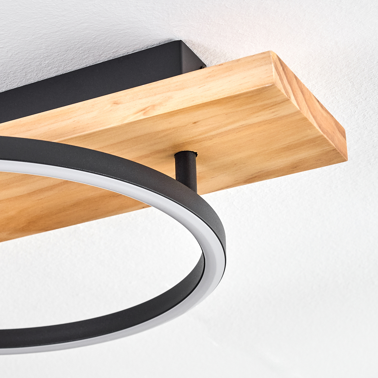 Eine moderne Deckenleuchte. Sie hat eine Holzbasis, einen schwarzen Metallrahmen und ein kreisförmiges LED-Licht.