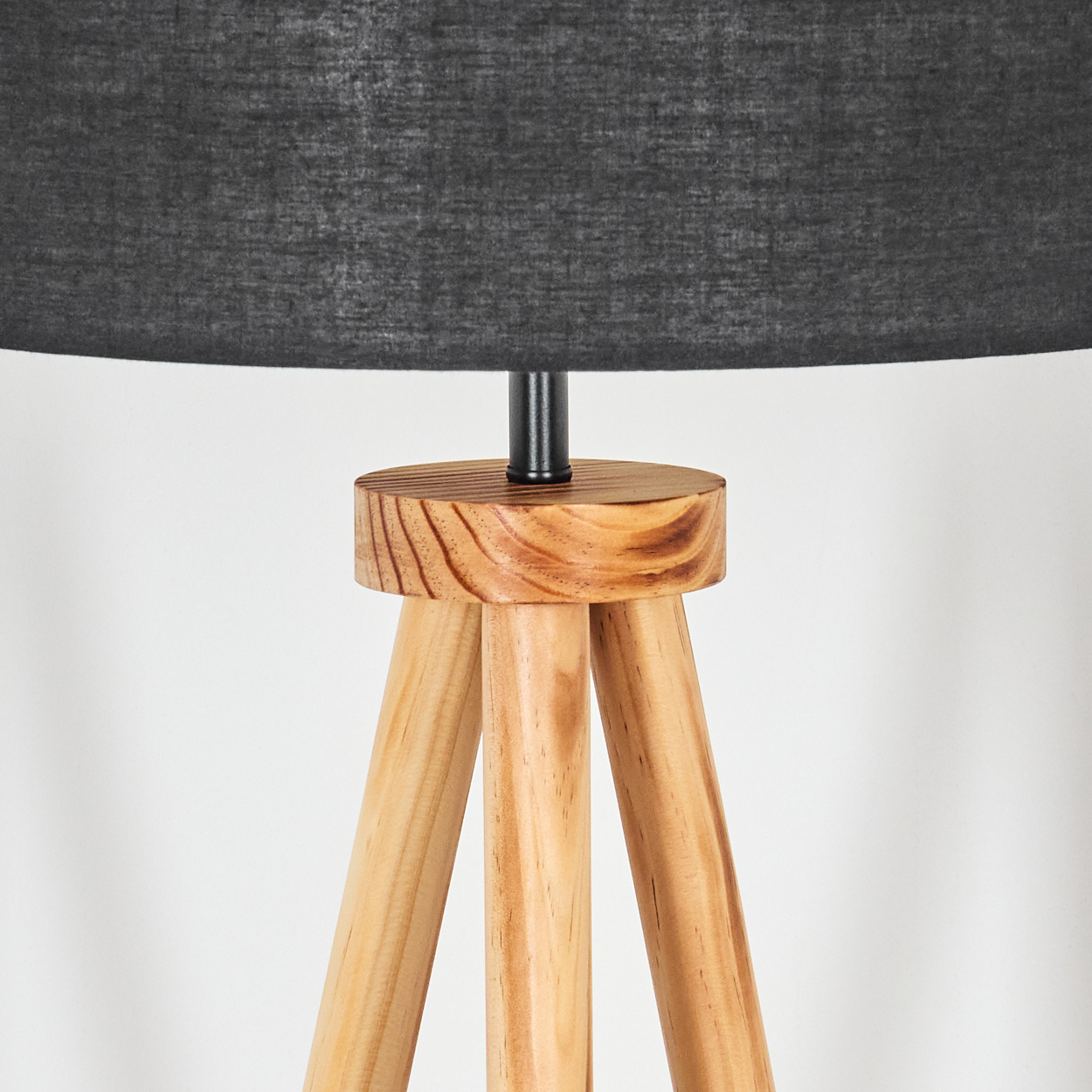 Eine hölzerne Stativlampe mit schwarzem Lampenschirm. Die Lampe hat einen Holzsockel und Beine sowie eine schwarze Metallstütze.