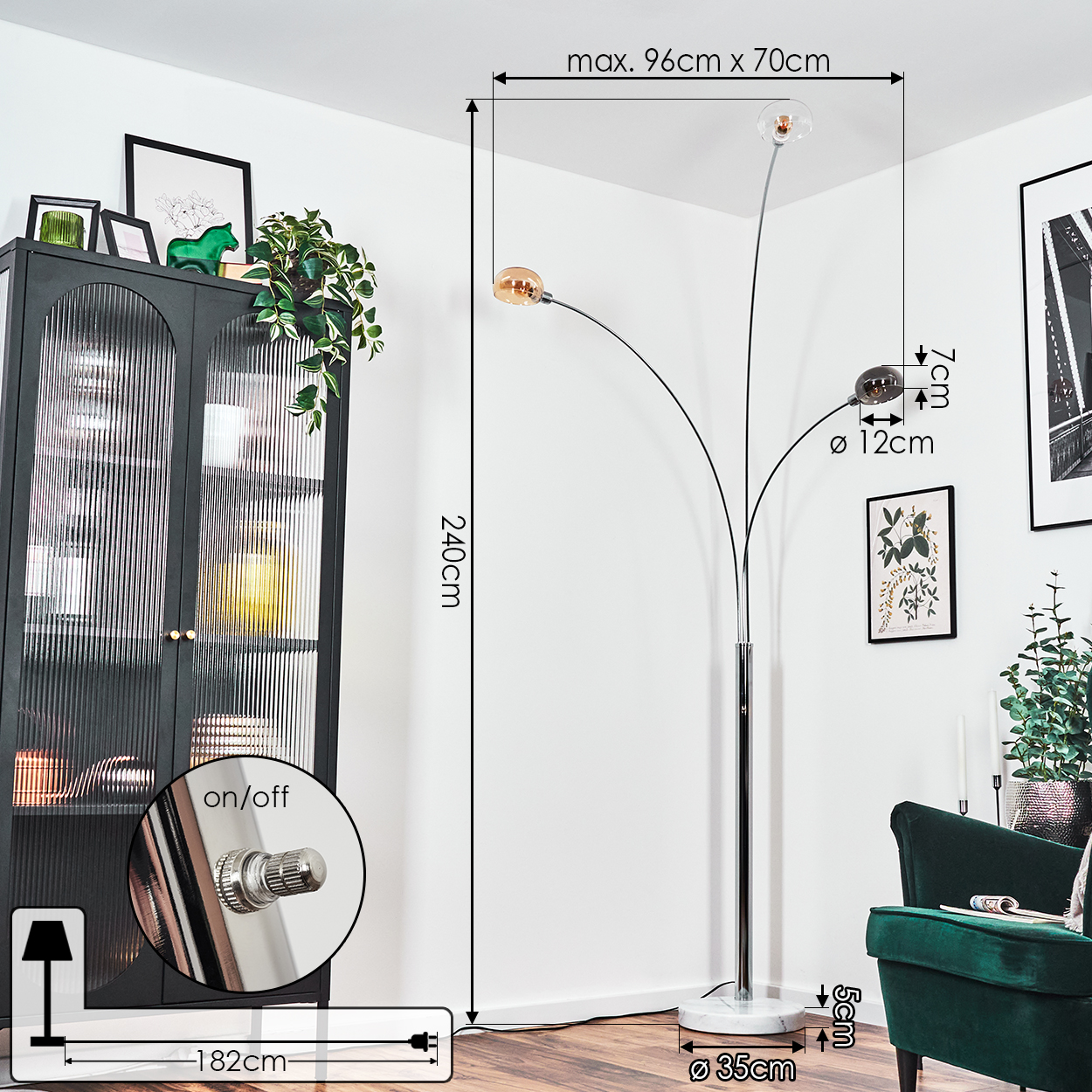 Eine moderne Stehlampe mit drei Glühbirnen. Ein schwarzer Schrank, ein grüner Sessel und gerahmte Kunst im Hintergrund.