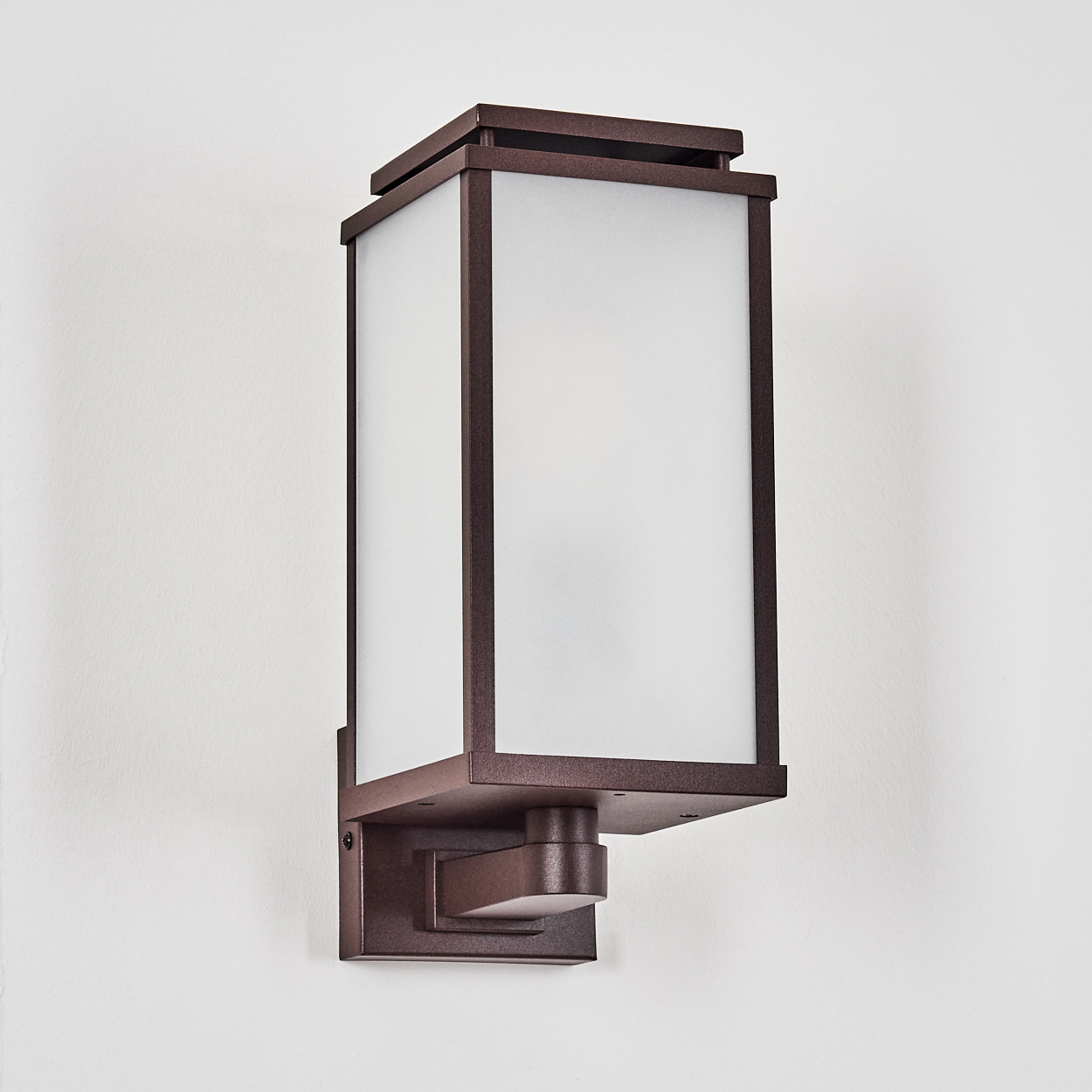 Eine bronzefarbene Wandleuchte mit rechteckigem, mattiertem Glasschirm und quadratischer Oberseite an weißer Wand.