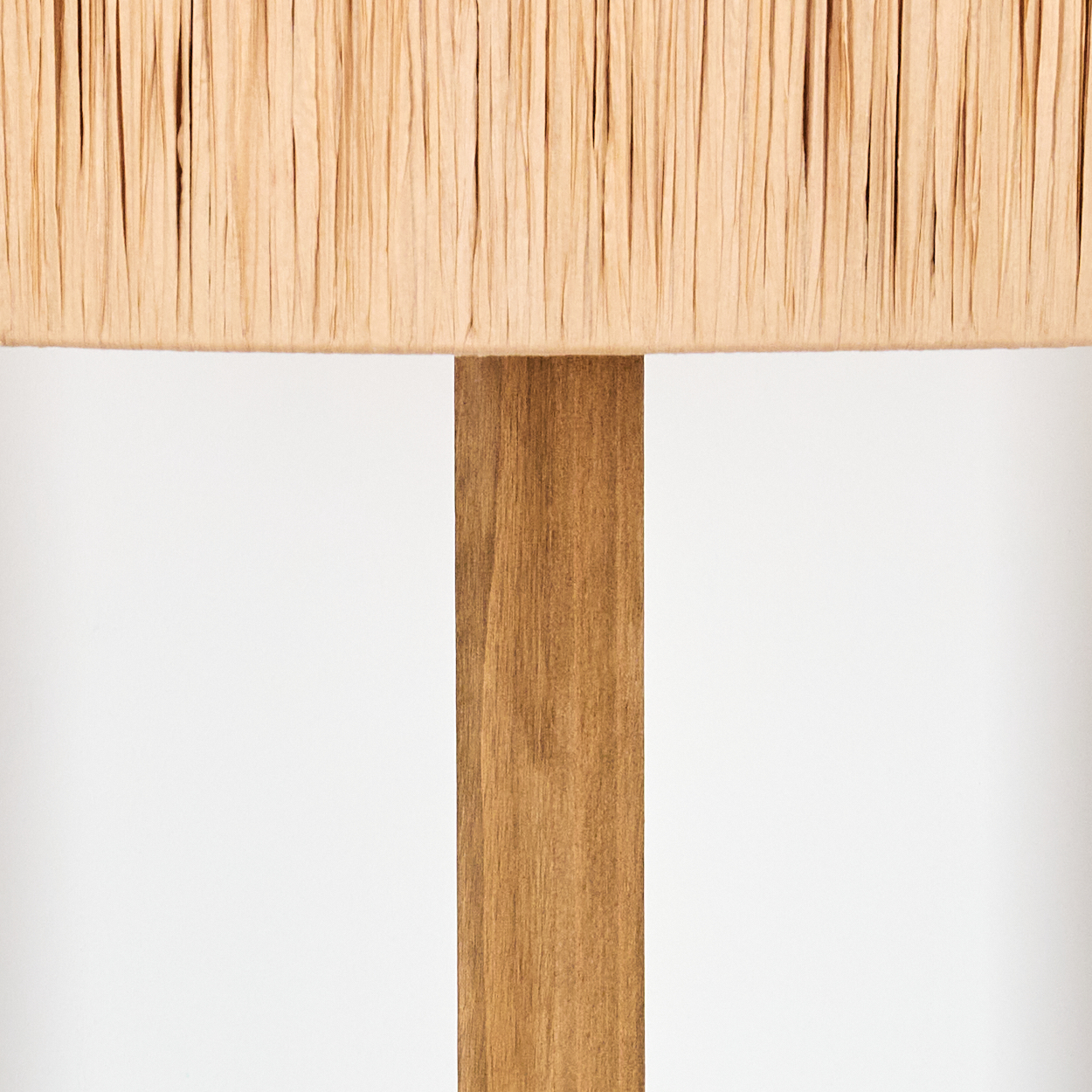 Eine hellfarbene Lampe mit beigefarbenem Lampenschirm und braunem Holzgestell, vor weißem Hintergrund.