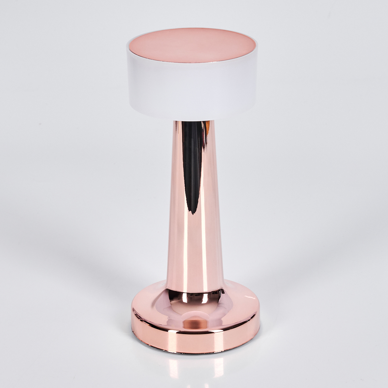 Eine moderne Tischlampe mit roségoldenem Sockel und Stiel, weißem Schirm und roségoldenem Oberteil. Vor weißem Hintergrund.