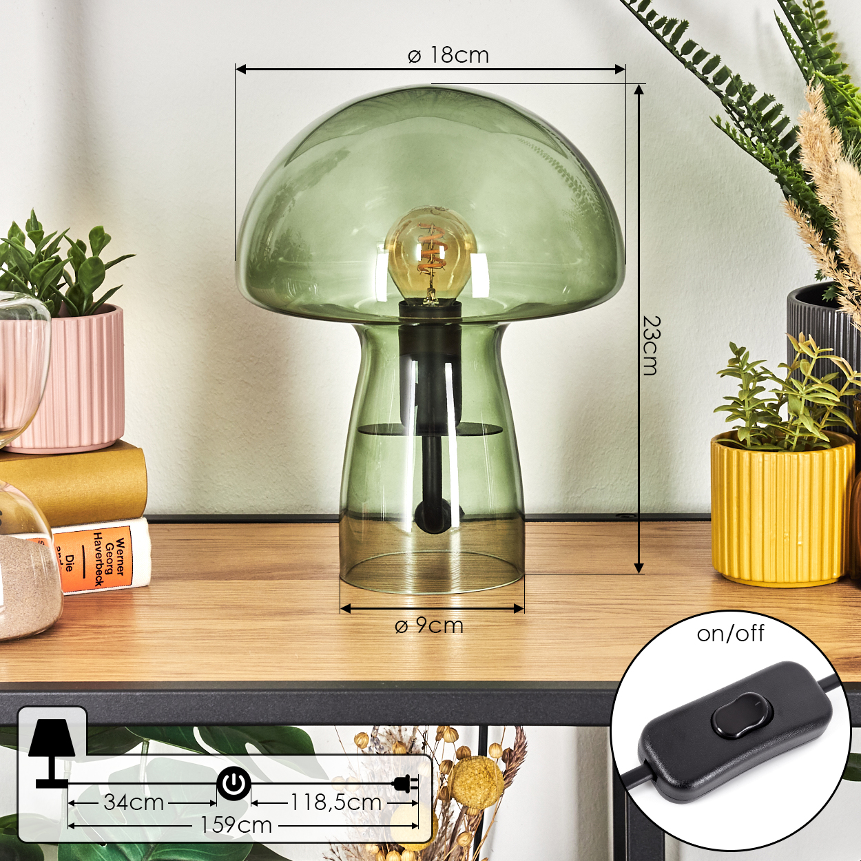Eine grüne pilzförmige Lampe steht auf einem Holzregal in der Nähe von Pflanzen in rosa und gelben Töpfen. Maße sind angegeben. Ein Ein/Aus-Schalter ist sichtbar.