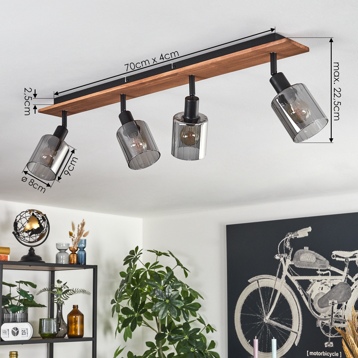 Deckenleuchte mit vier Lichtern. Abmessungen sind beschriftet. Hintergrund umfasst Dekor, Pflanzen und ein Motorrad-Kunstwerk.