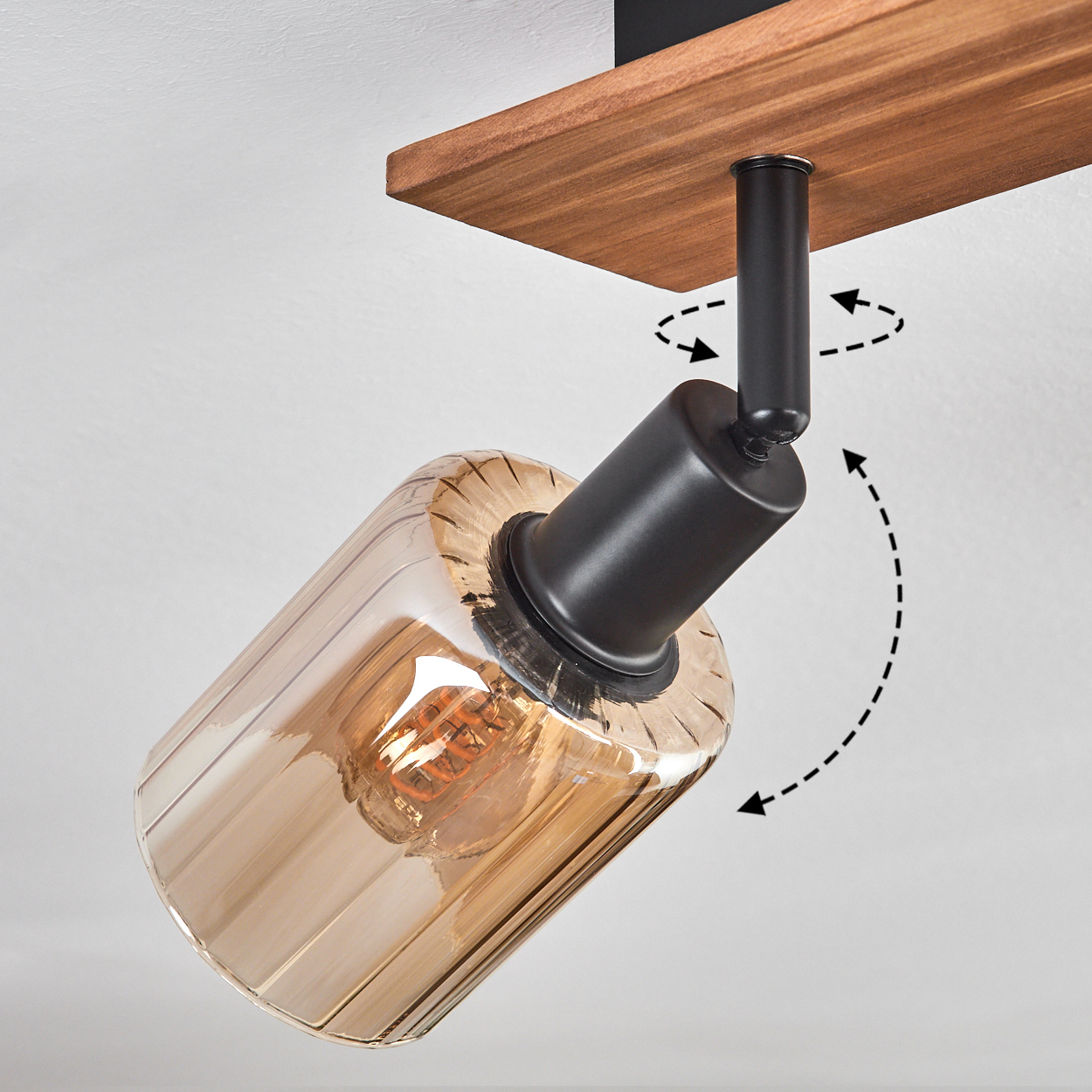 Eine moderne Spot-Lampe mit braunem Holzsockel und transparentem, bernsteinfarbenem Glasschirm. Die Lampe ist schwarz und verstellbar.