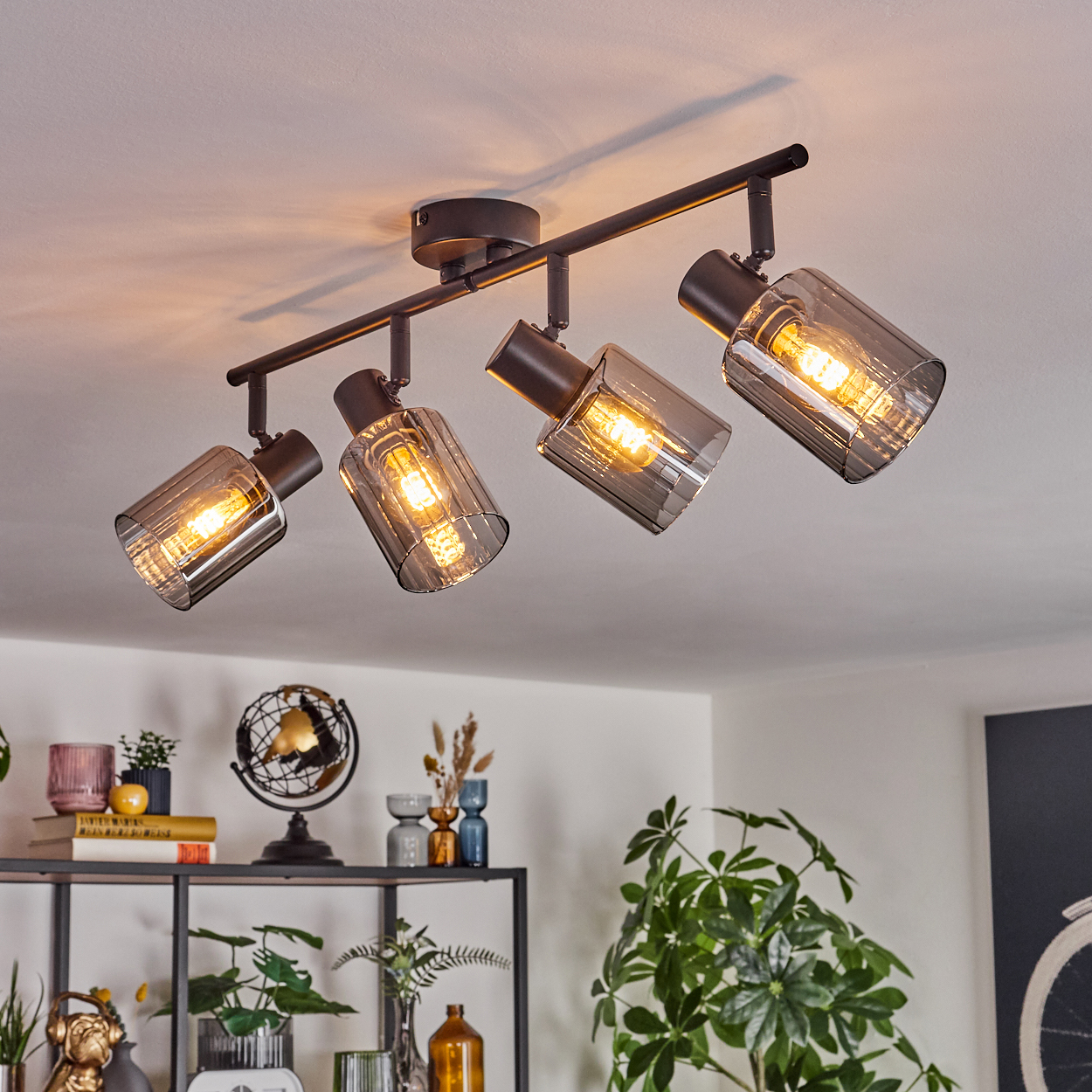 Moderne Deckenleuchte mit vier Strahlern. Der Raum hat eine Dekoration mit Pflanzen, Regalen und Dekorationsartikeln.