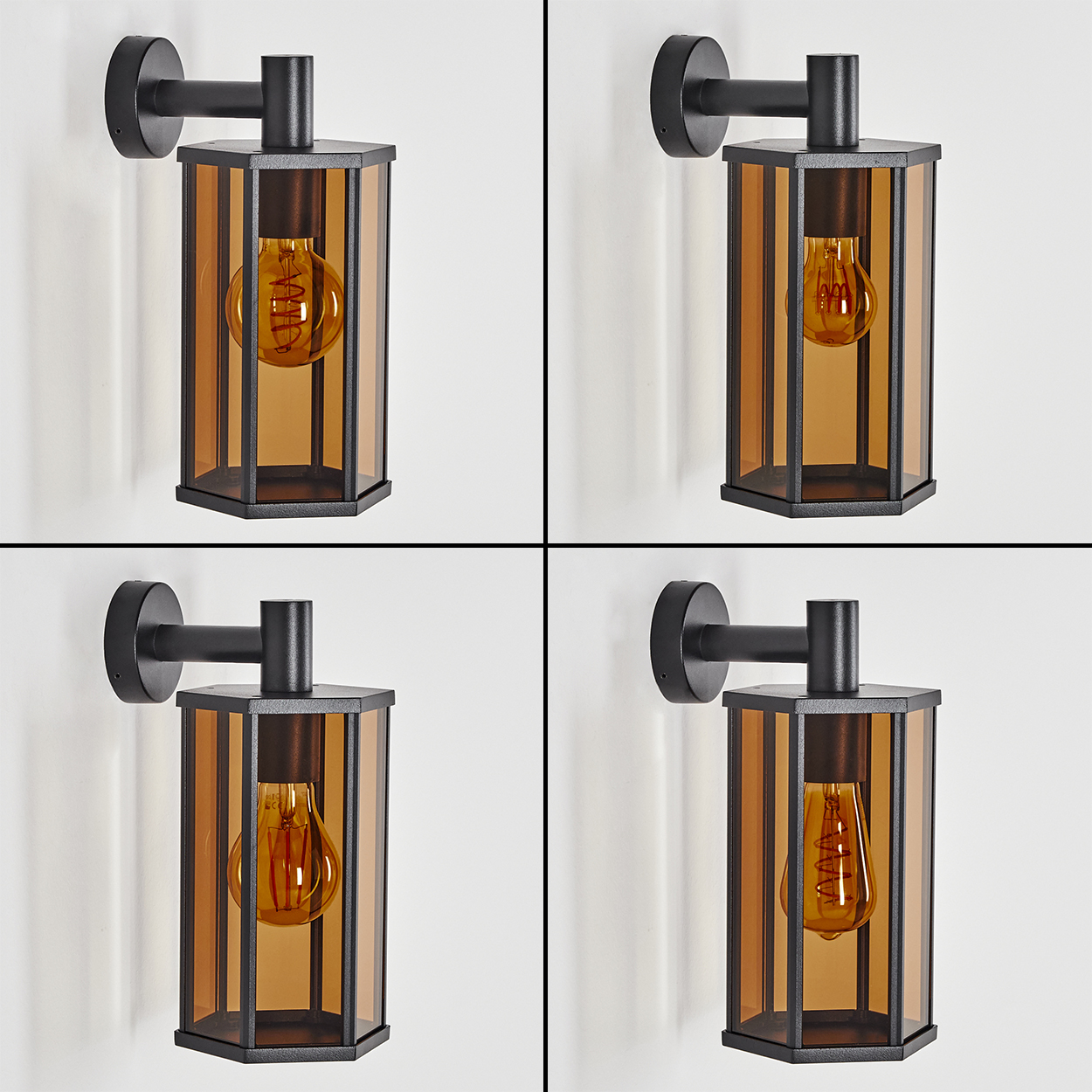Vier schwarze Wandleuchten mit bernsteinfarbenem Glas und Edison-Glühbirnen vor einer weißen Wand.
