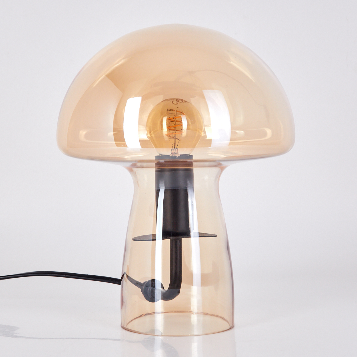 Eine pilzförmige Lampe mit braunem Glasschirm. Eine Glühbirne ist innen. Der Sockel ist schwarz und hat ein schwarzes Kabel.