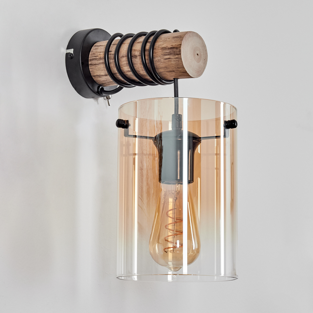 Eine Wandlampe mit Holzsockel, Glasschirm und sichtbarer Glühbirne. Die Lampe befindet sich vor einer weißen Wand.