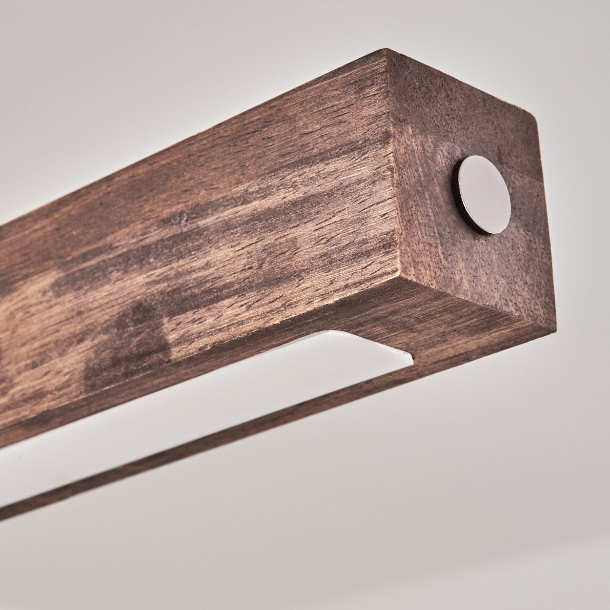 Nahaufnahme eines Holzbalkens mit sichtbarer Maserung, Metallscheibe und einem weißen Lichtstreifen, vor schlichtem weißem Hintergrund.