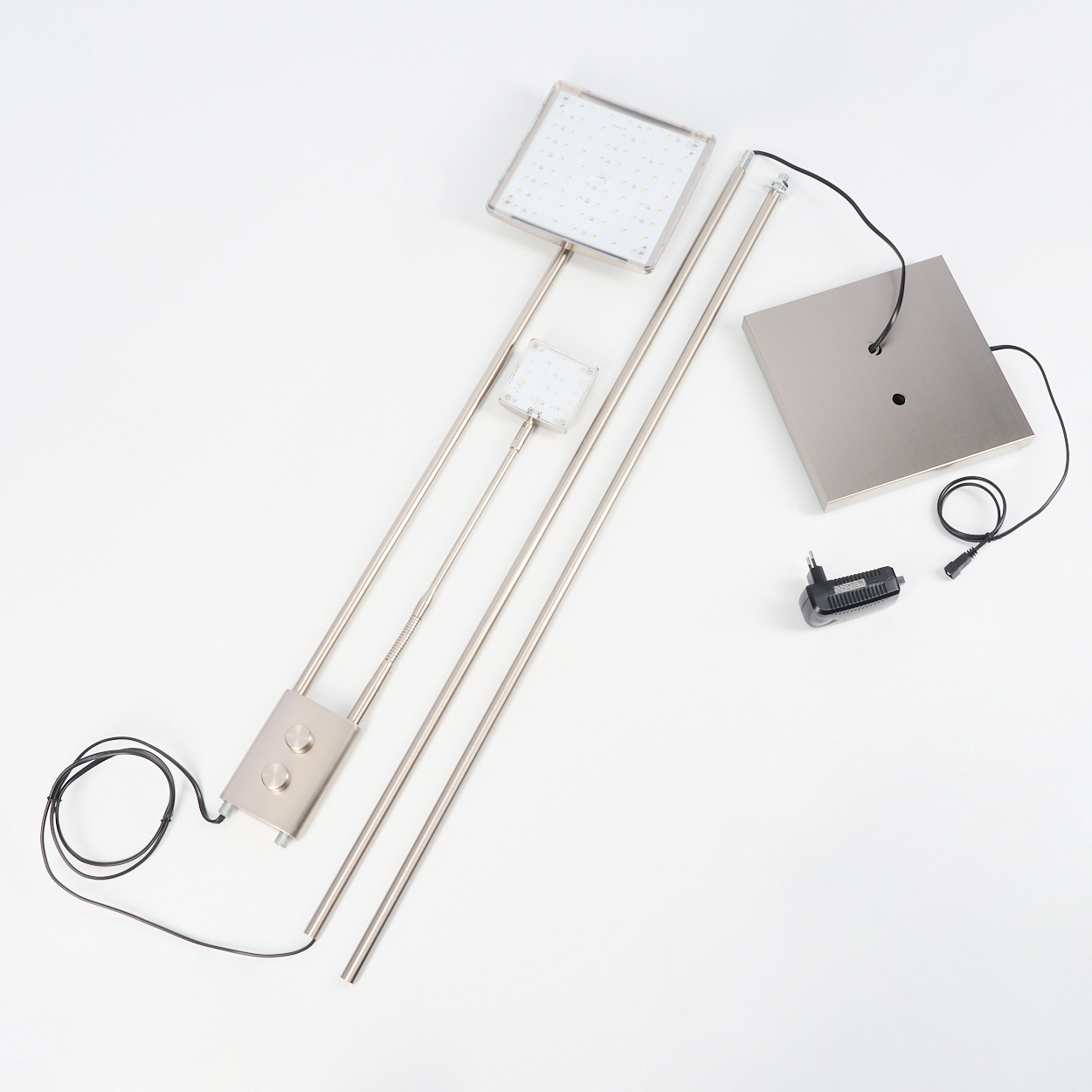Bestandteile einer Lampe auf weißer Oberfläche angeordnet. Enthält quadratische Lichtpaneele, Metallstangen, einen Sockel und einen Netzadapter.