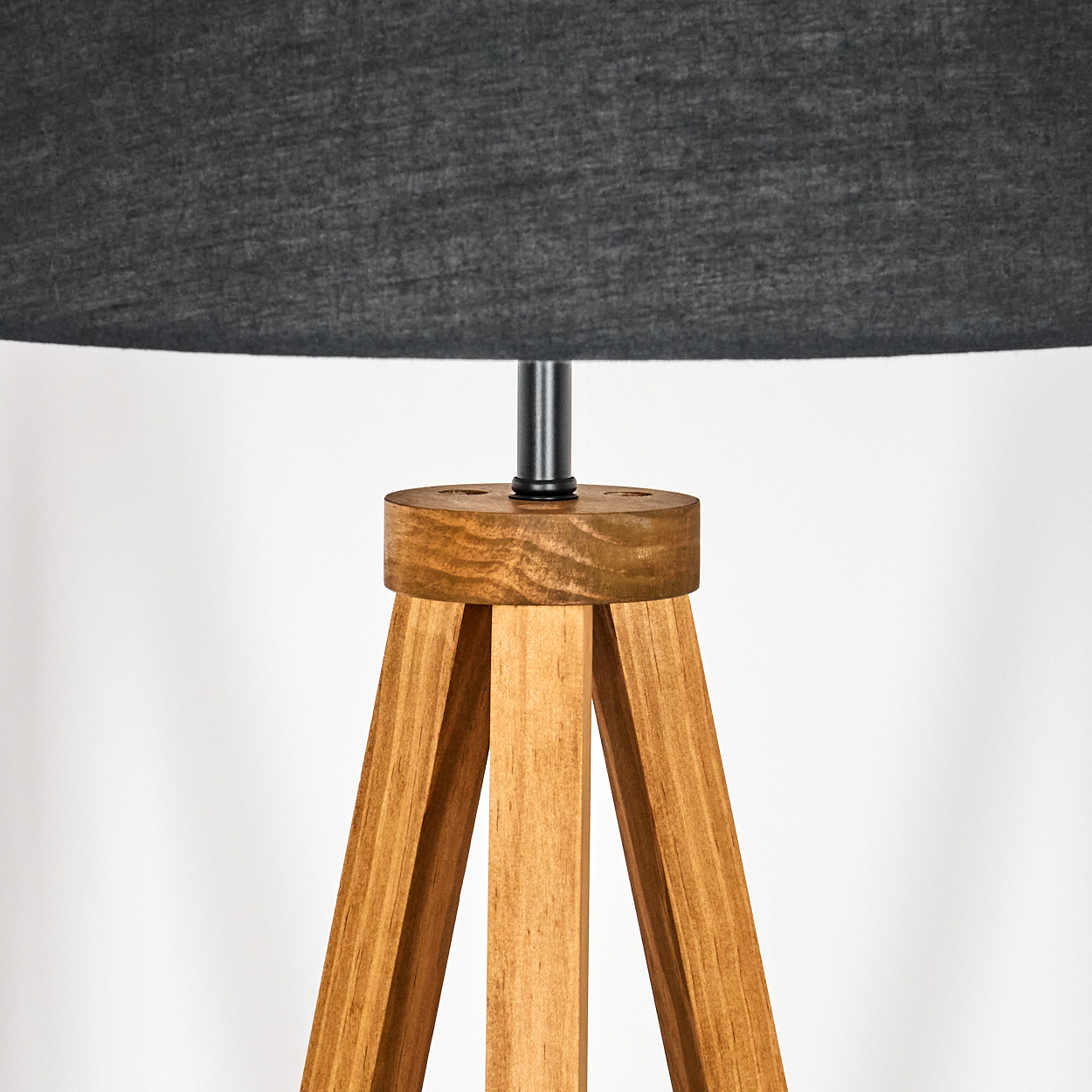 Eine hölzerne Stativlampe mit grauem Lampenschirm. Die Lampe hat einen Holzfuß und eine schwarze Metallstange, die den Schirm trägt.