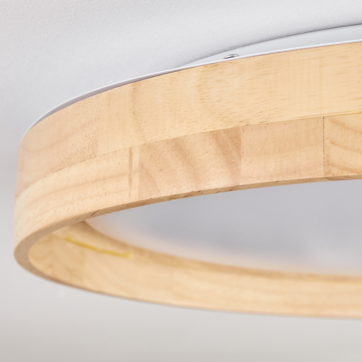 Nahaufnahme einer kreisförmigen Holzleuchte an einer weißen Decke. Das Holz hat eine natürliche, helle Farbe.