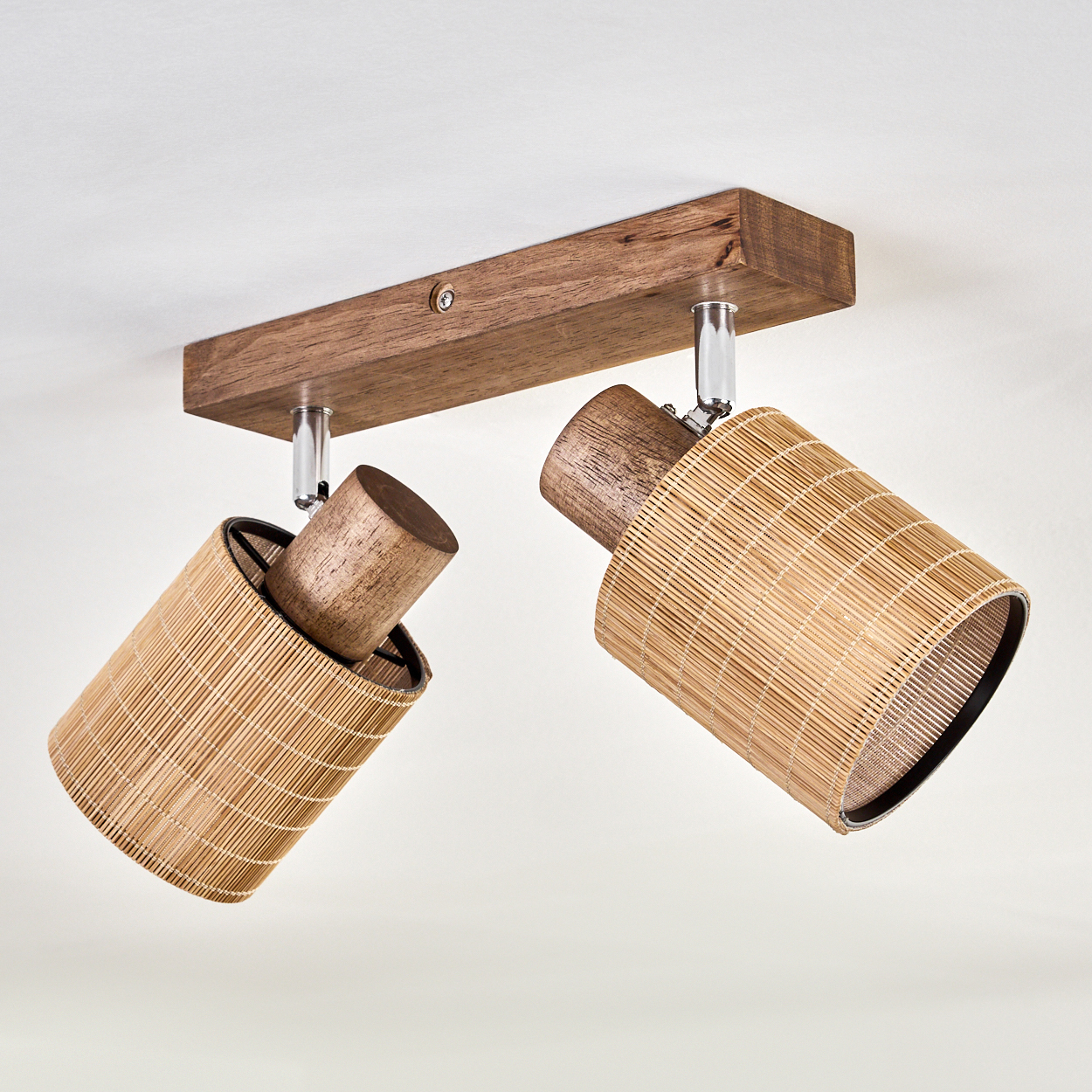 Eine Deckenleuchte mit zwei Lampen. Die Lampen bestehen aus geflochtenem Bambus und Holz. Der Hintergrund ist eine weiße Decke.