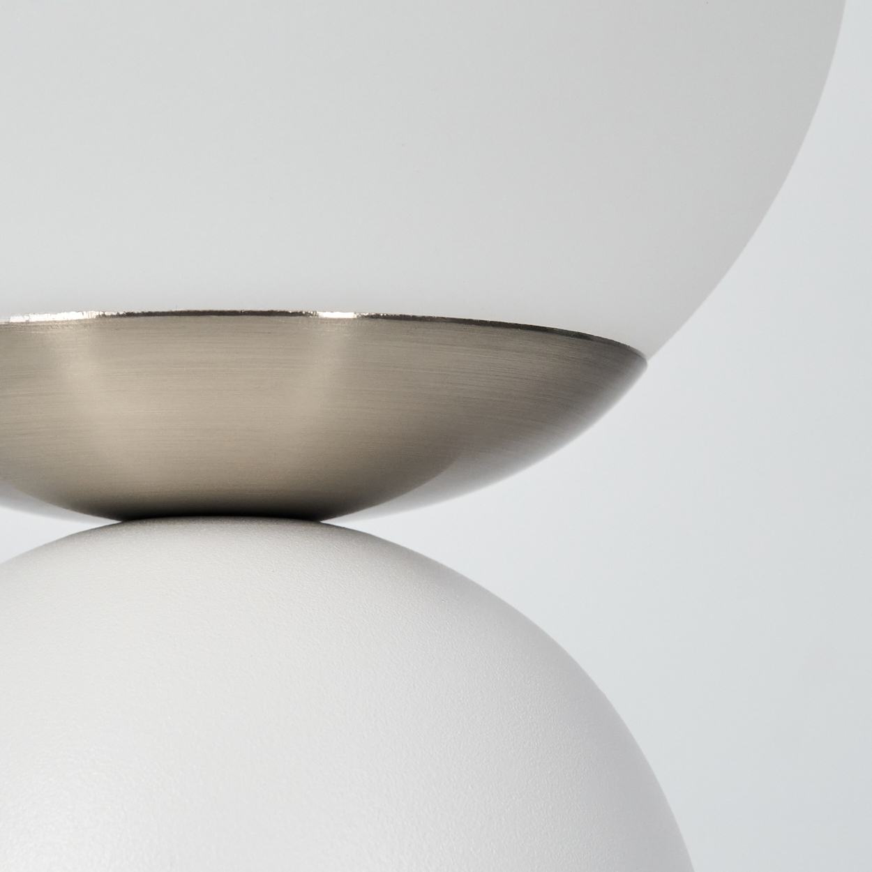 Nahaufnahme einer modernen Lampe. Zwei weiße, abgerundete Abschnitte werden durch ein metallisch-graues Band getrennt.