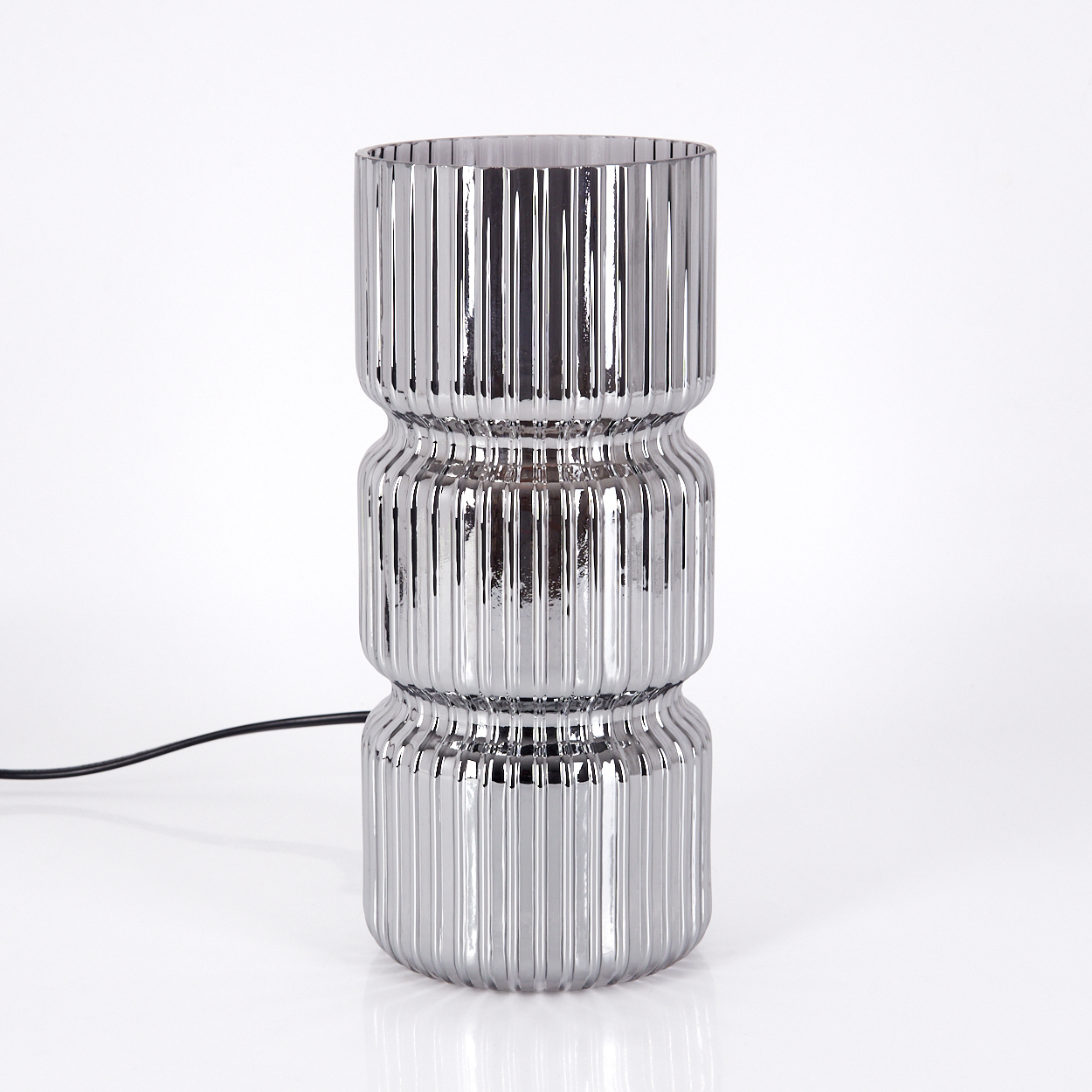 Eine verchromte Lampe mit vertikal geripptem Design, drei gestapelten Abschnitten und einem schwarzen Netzkabel.