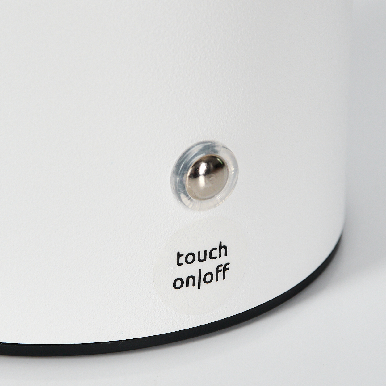 Nahaufnahme eines weißen Objekts mit einer Touch-Ein/Aus-Taste und einer silbernen Taste. Das Objekt hat einen schwarzen Sockel.