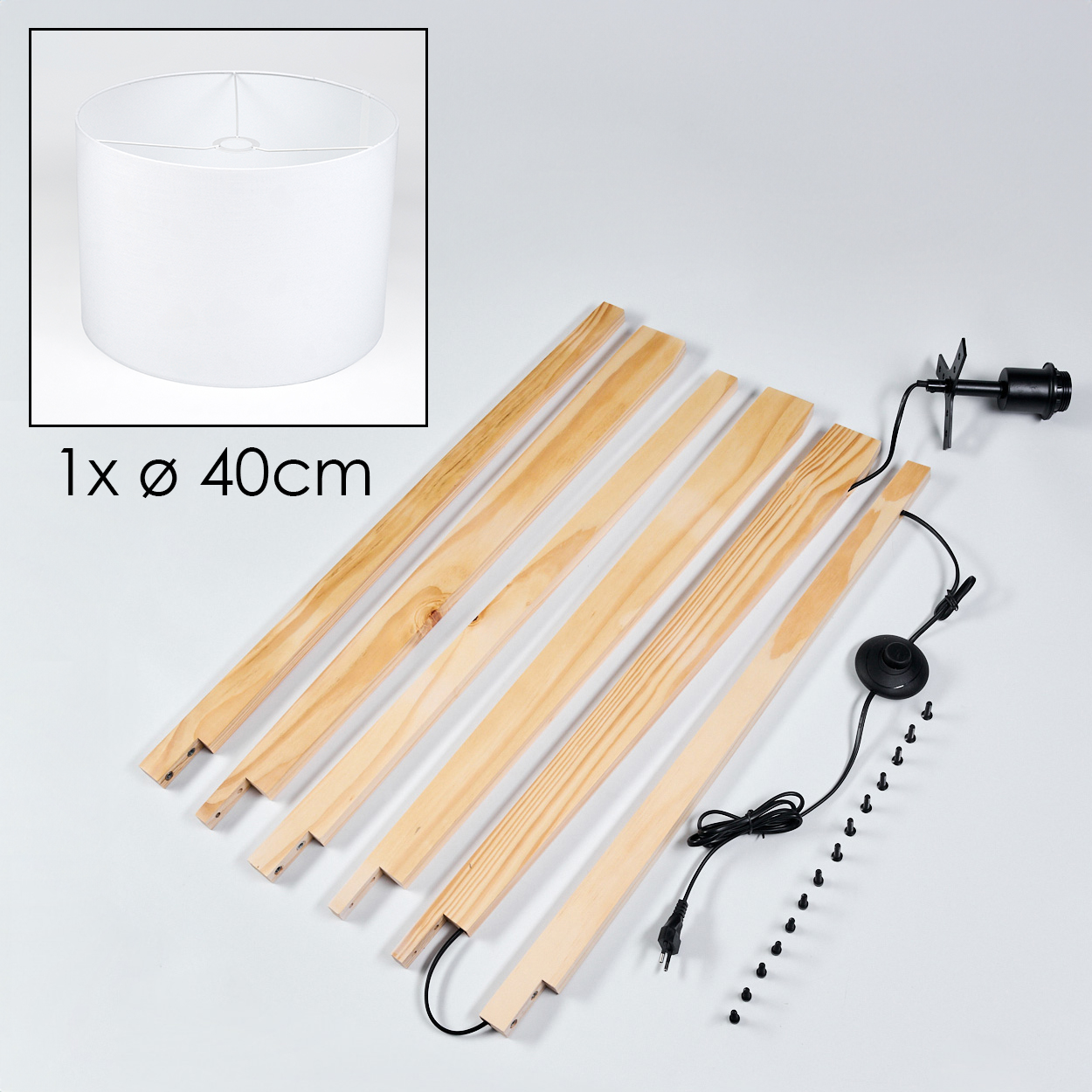 Ein Lampenbausatz mit weißem Lampenschirm, Holzstützen, einer Leuchte, einem Fußschalter, Schrauben und einem Netzkabel.