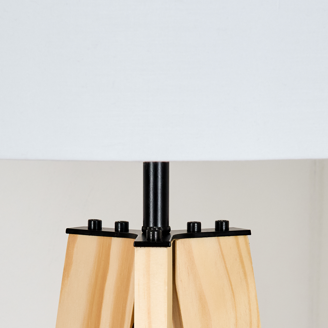 Eine Lampe mit weißem Lampenschirm und Holzsockel. Der Sockel besteht aus hellem Holz mit schwarzen Metalldetails.
