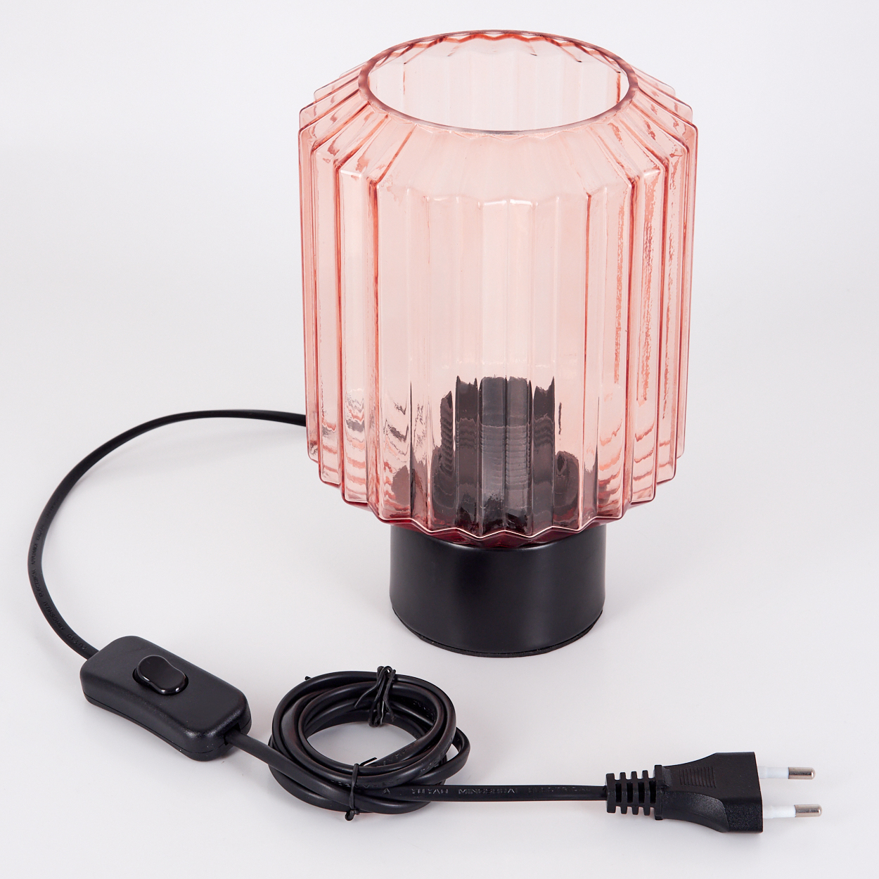 Eine rosa Glaslampe mit schwarzem Sockel, Kabel und Stecker liegt auf weißem Untergrund.