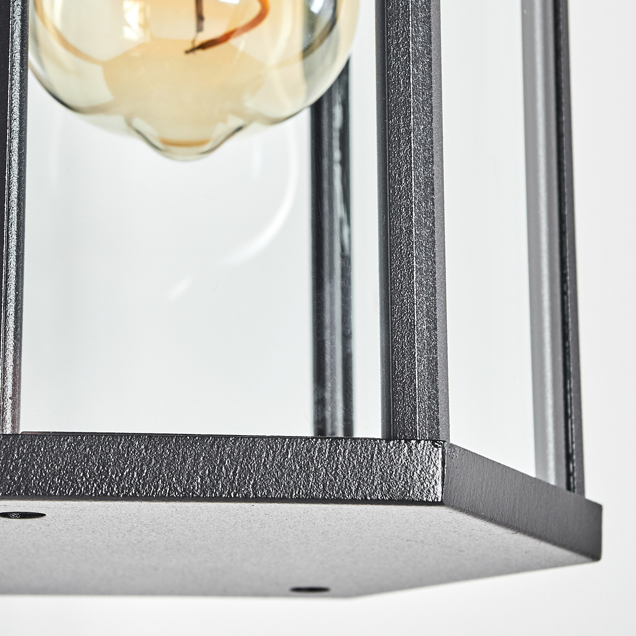 Nahaufnahme einer schwarzen Metalllaterne mit Glasscheiben. Im Inneren ist eine Glühbirne zu sehen, mit weißem Hintergrund.