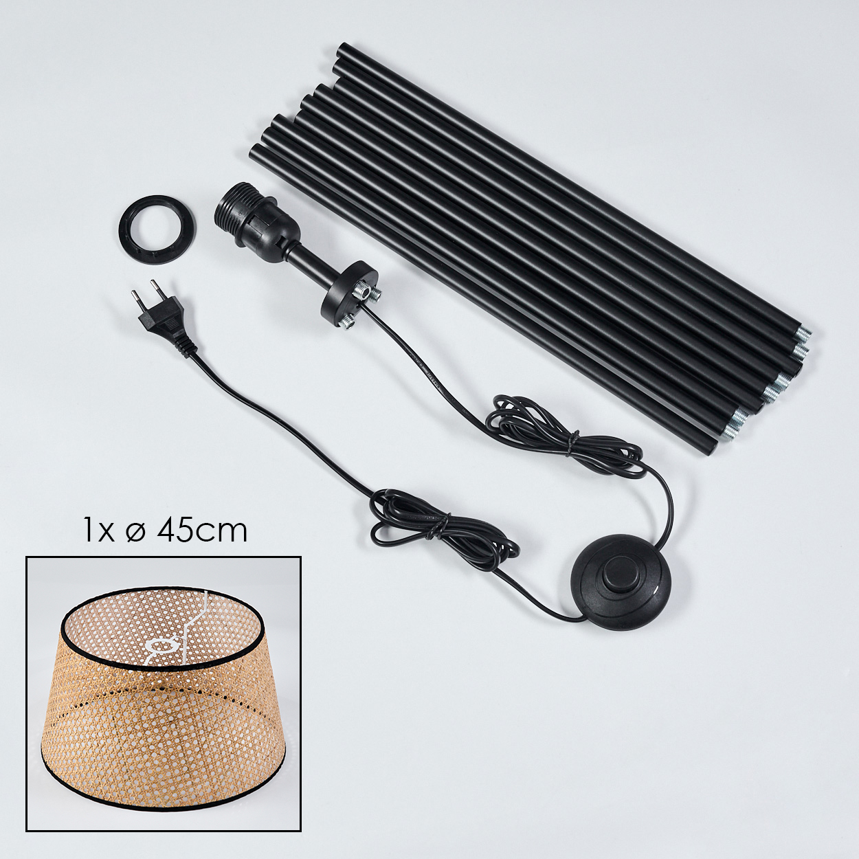 Komponenten einer Stehlampe auf weißem Untergrund. Enthält schwarze Stangen, einen Lampenschirm, eine Glühbirnenfassung, Kabel und einen Fußschalter.