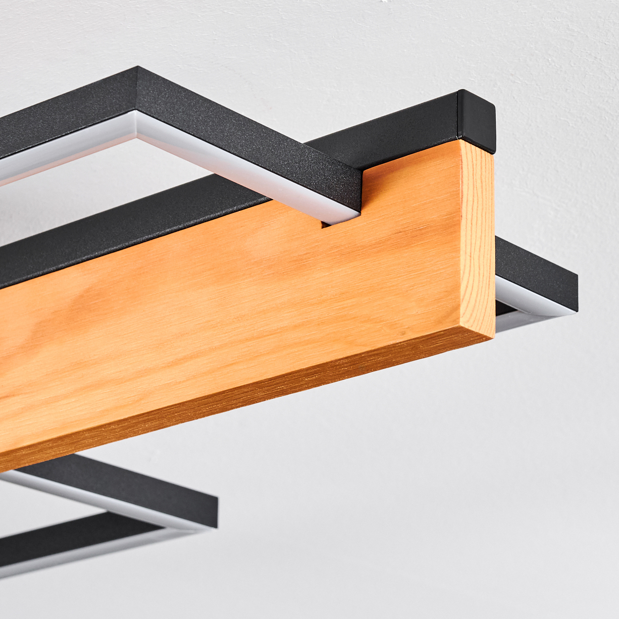 Eine moderne Leuchte mit Holzbalken und schwarzem Metallrahmen. Weißes Licht geht vom Rahmen aus.