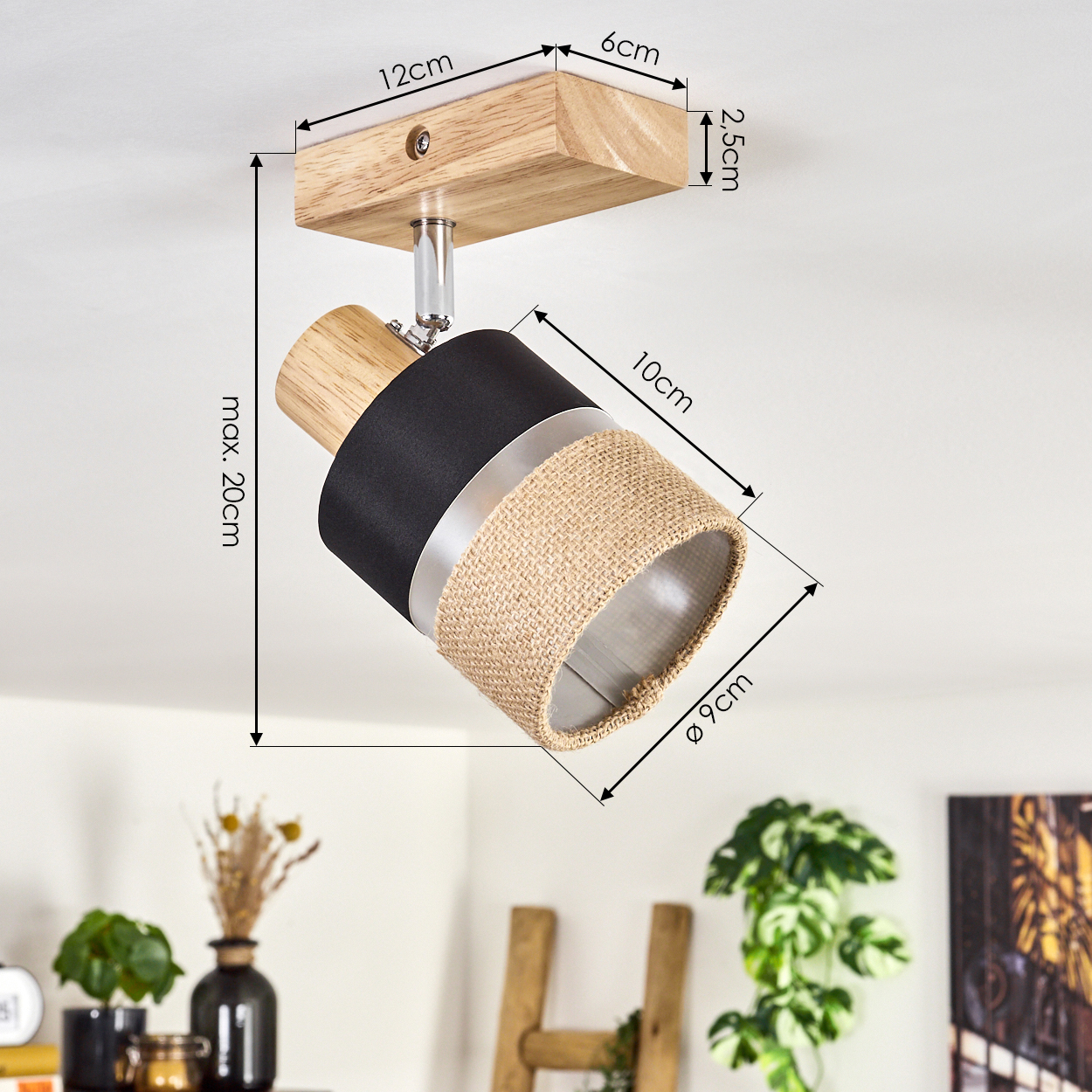 Ein Deckenstrahler mit Holz, schwarzem Stoff und gewebtem beigefarbenem Schirm wird angezeigt. Maße sind beschriftet. Pflanzen und Deko sind im Hintergrund.