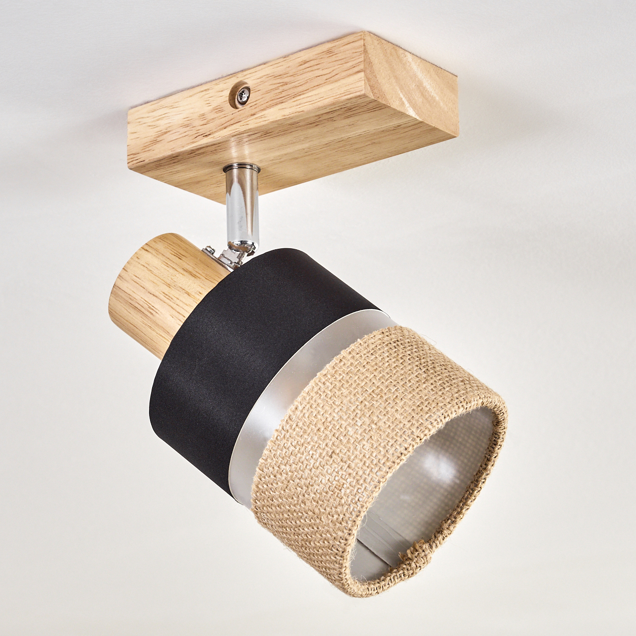 Deckenstrahler mit Holzsockel. Die Lampe hat einen schwarzen, silbernen und beigen Schirm. Der Hintergrund ist weiß.