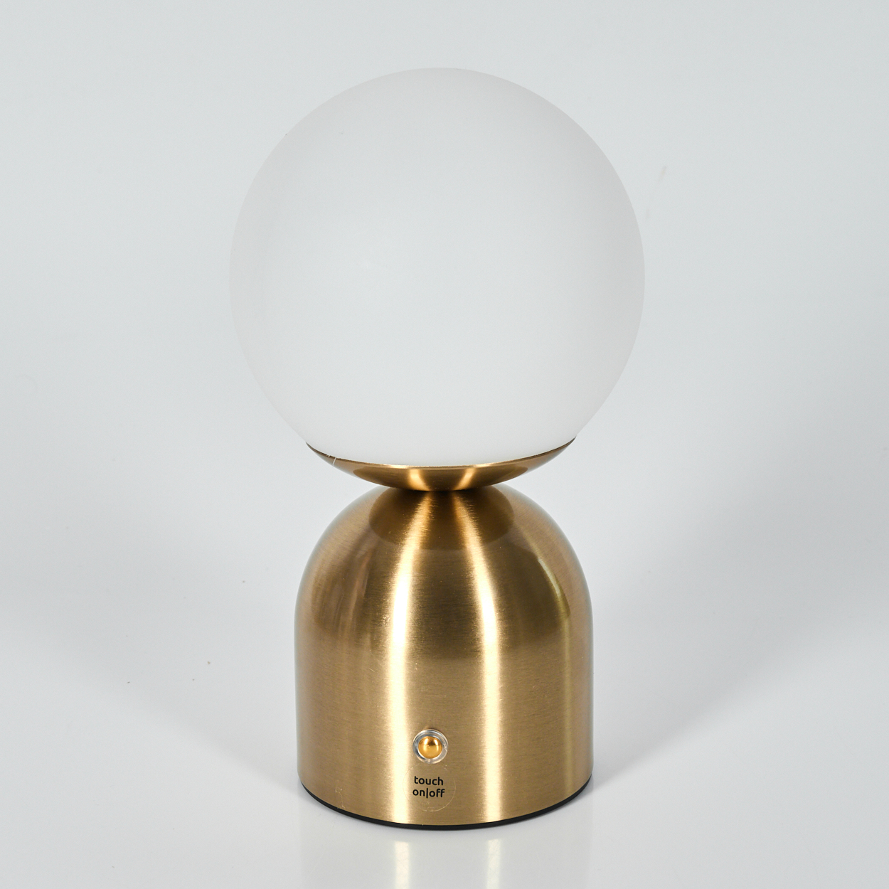 Eine moderne Tischlampe mit rundem, weißem Glasschirm auf goldenem Sockel. Sie hat eine Touch-Ein-/Aus-Taste.
