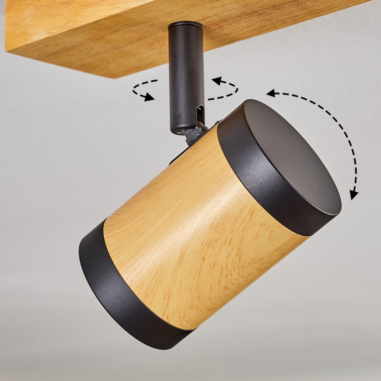 Ein Deckenstrahler mit Holzgehäuse und schwarzen Akzenten, montiert an einem Holzbalken. Pfeile zeigen die einstellbare Richtung.