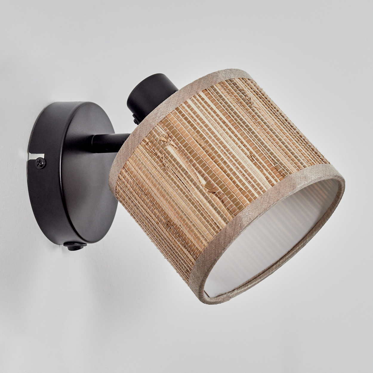 Eine Wandlampe mit zylindrischem Lampenschirm. Der Schirm besteht aus gewebtem beigen Material und ist an einem schwarzen Arm und Sockel befestigt.