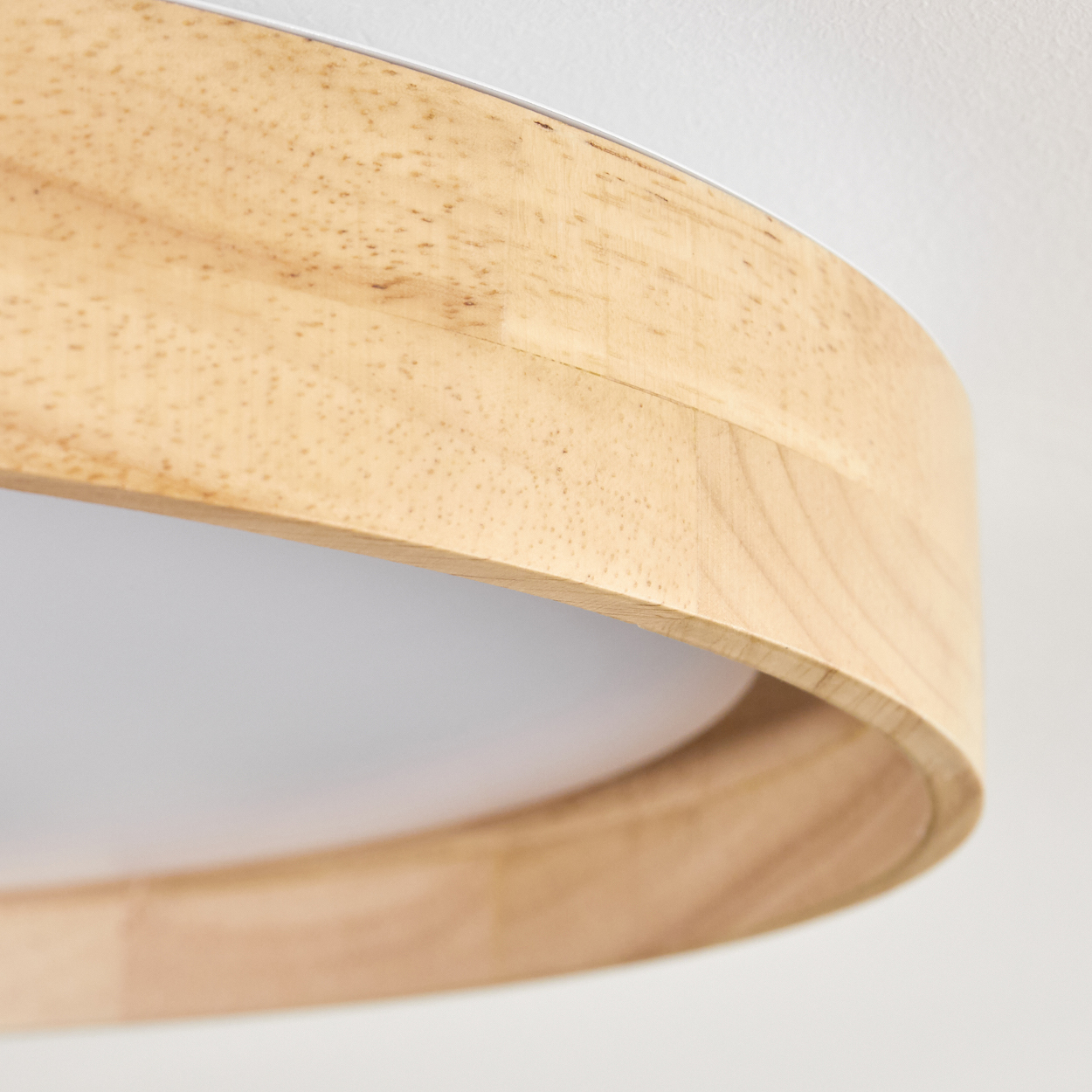 Nahaufnahme einer Holzlampe. Die Lampe hat eine helle Holzoberfläche und einen weißen Innenraum. Der Hintergrund ist weiß.