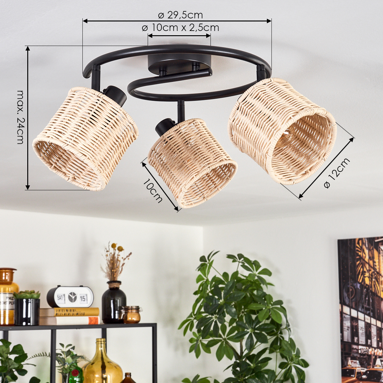 Deckenlampe mit drei Lichtern und Korbschirmen. Darunter ein Regal mit Deko und einer Pflanze. Im Hintergrund eine Pflanze und ein Bild.