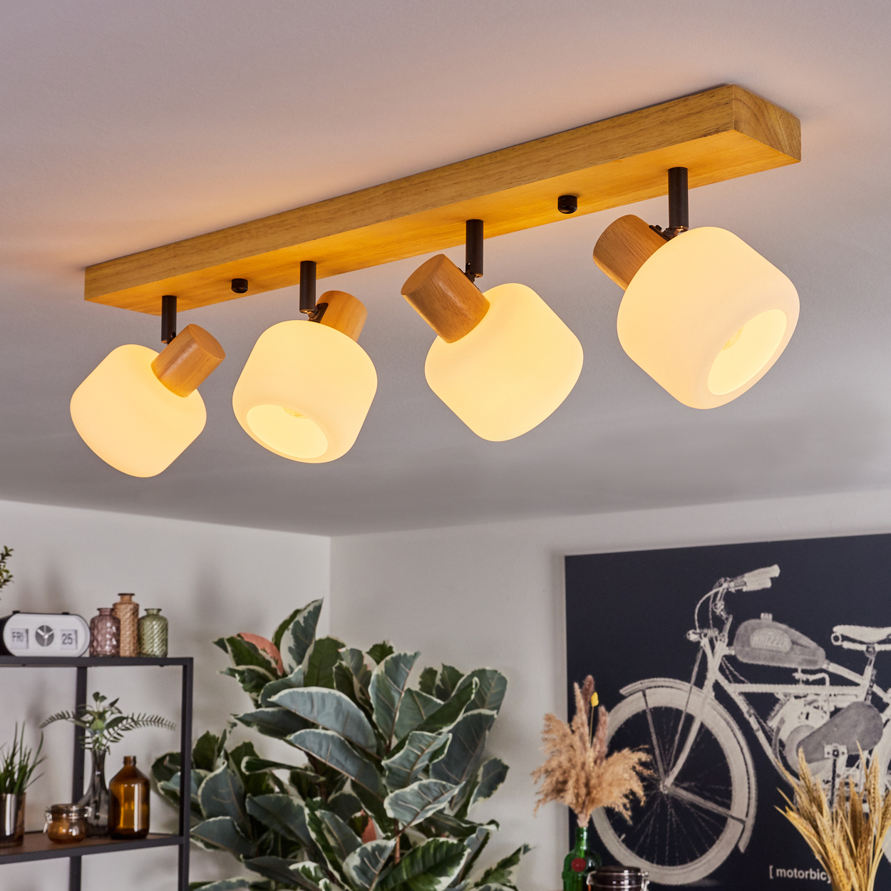 Deckenleuchte mit vier Lampen. Holzbalken, Glasschirme und eine Pflanze im Vordergrund.