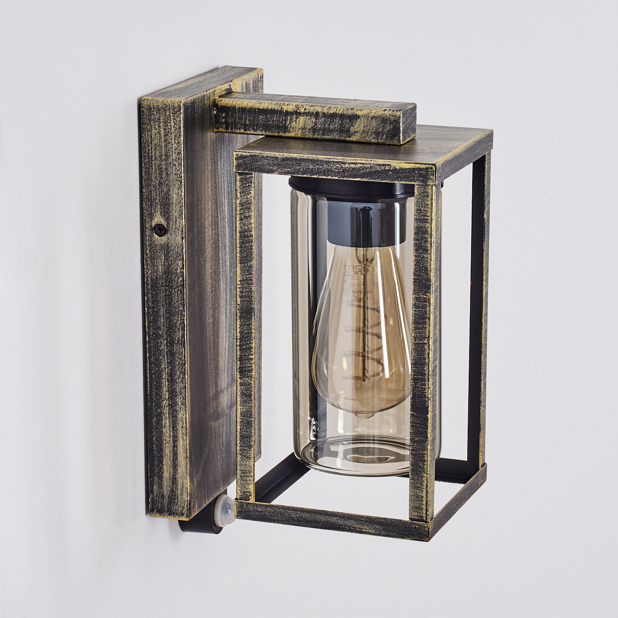 Eine Außenwandleuchte. Sie hat einen rechteckigen Rahmen mit einem Glasgehäuse, einer Glühbirne im Inneren und einem holzähnlichen Finish.