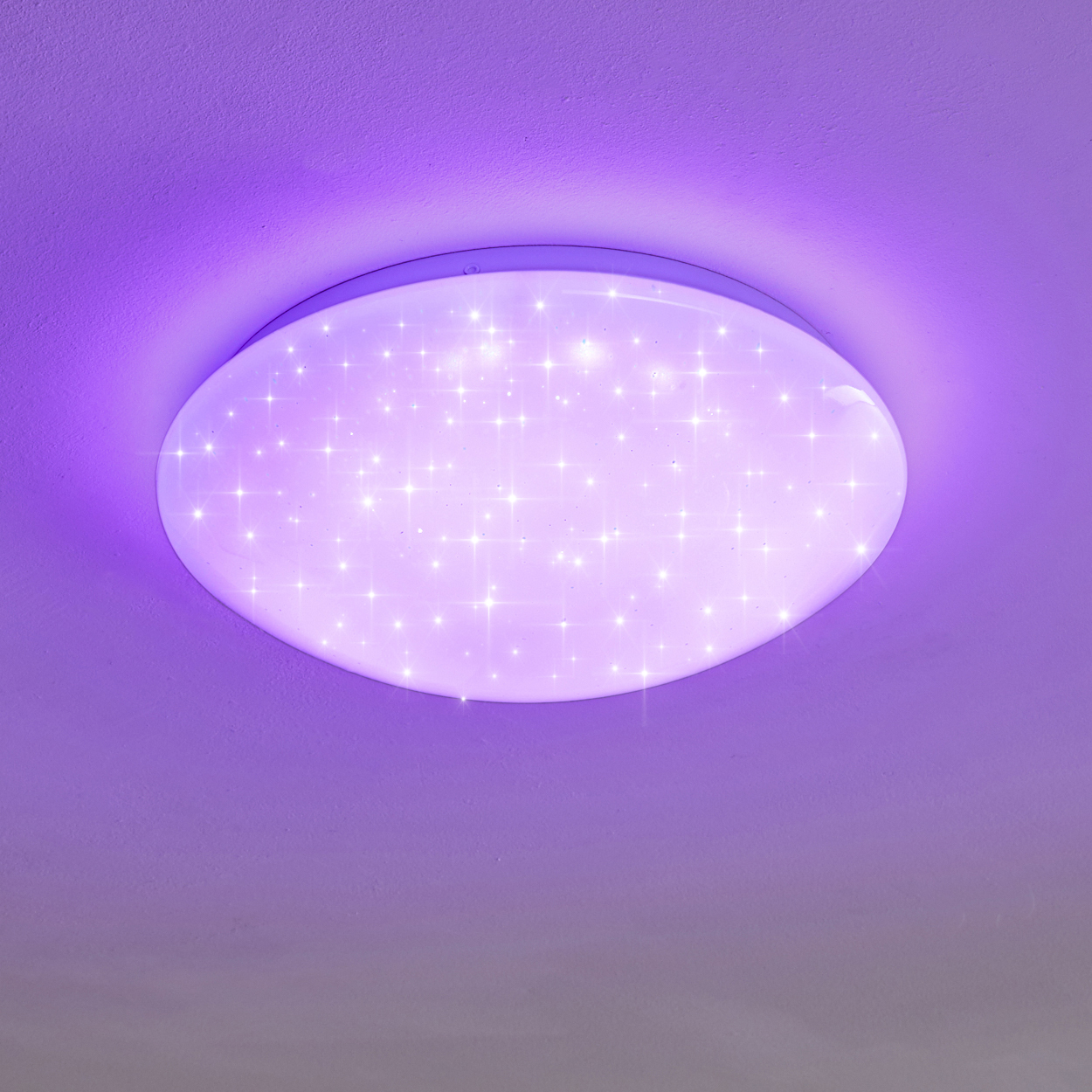 Eine ovale Deckenleuchte strahlt ein sternenähnliches Leuchten auf einem lila Hintergrund aus. Die Leuchte ist weiß und rund, die Decke ist lila.