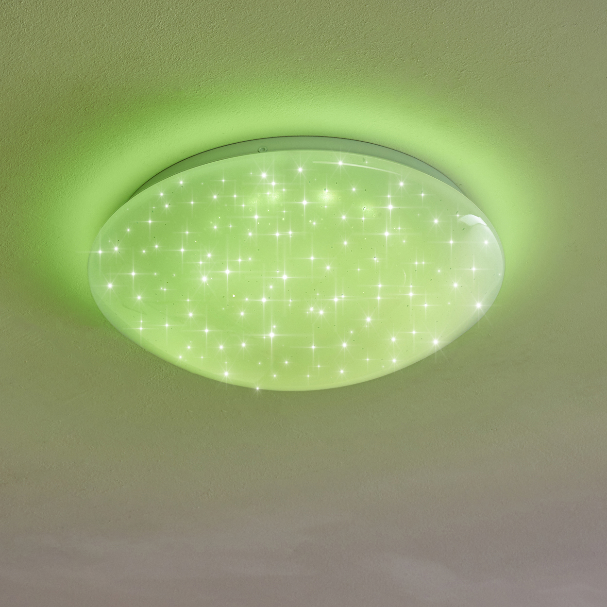 Eine runde Deckenleuchte mit grünem Schein. Das Licht hat ein Sternenmuster und ist an einer grünen Decke montiert.