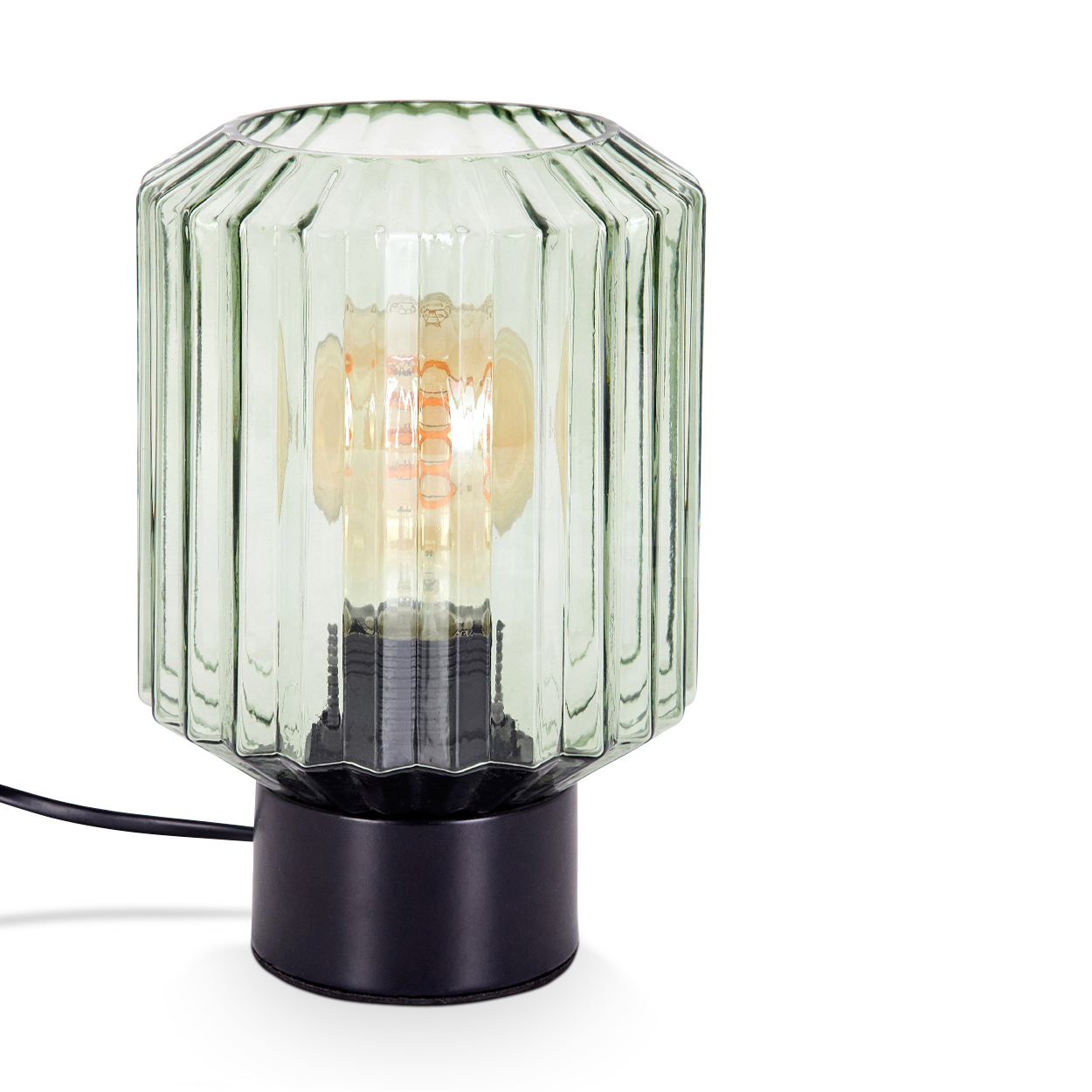Eine gerippte Lampe aus grünem Glas mit schwarzem Sockel. Im Inneren befindet sich eine Glühbirne mit sichtbarem Glühfaden. Die Lampe steht auf weißem Grund.