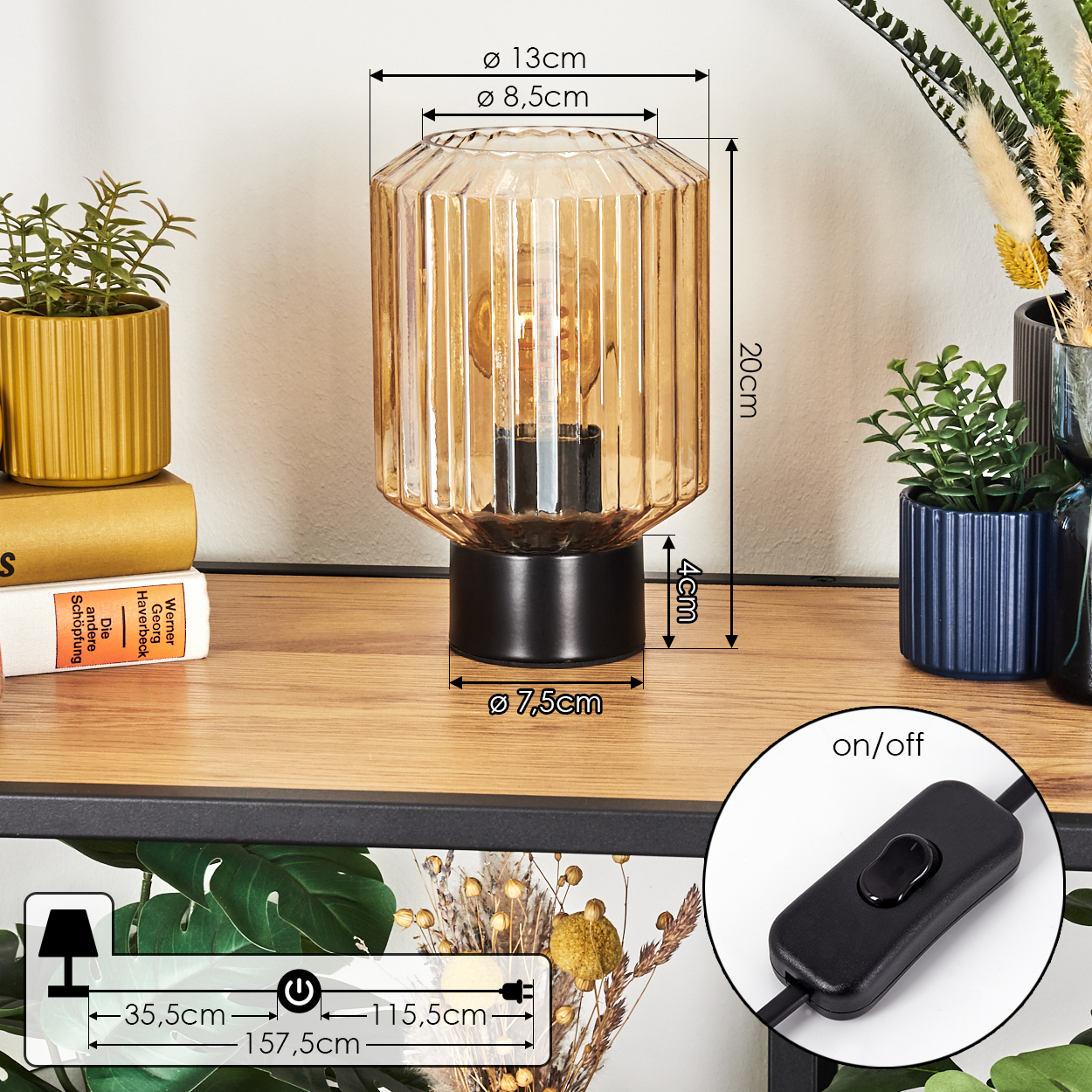 Eine dekorative Lampe mit schwarzem Sockel und bernsteinfarbenem Glas, Maße angegeben. Pflanzen und Bücher neben der Lampe. Ein/Aus-Schalter.