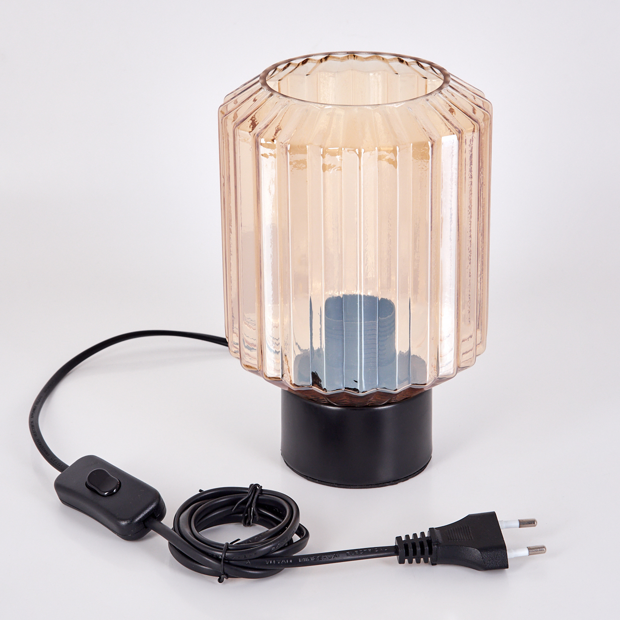 Eine kleine Tischlampe mit schwarzem Fuß und bernsteinfarbenem Glasschirm. Sie hat ein schwarzes Kabel und einen Stecker.