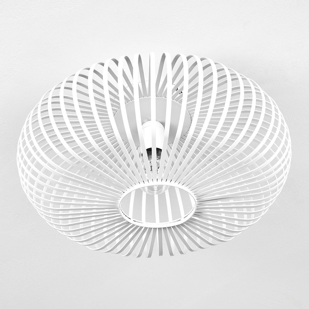 Eine weiße, moderne Deckenleuchte mit einem geschichteten, ovalen Design. Das Licht befindet sich an einer weißen Decke.